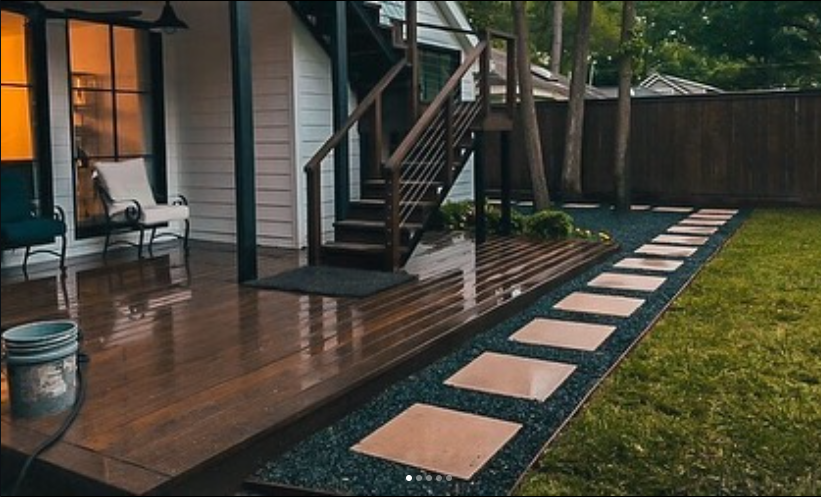 Backyard patio with a wooden deck, a set of stairs, a bench, and a stepping stone path across a grassy yard.