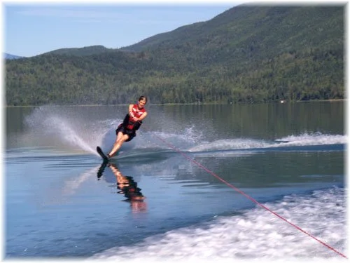 Person water skiing on a lake with mountains in the background.
