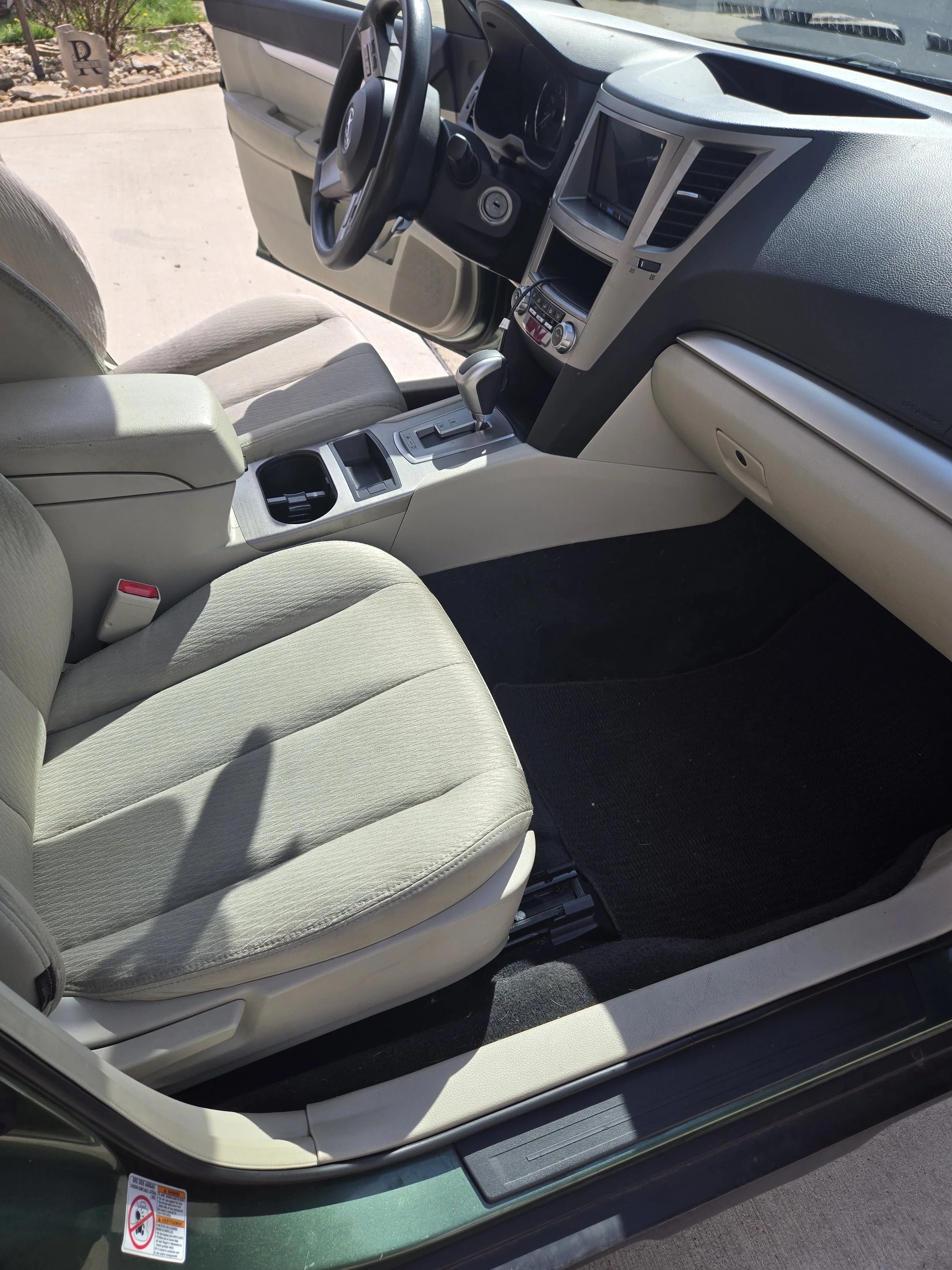 Interior of a car showing the front passenger seat, center console with gear shift, and dashboard with controls and display screen.