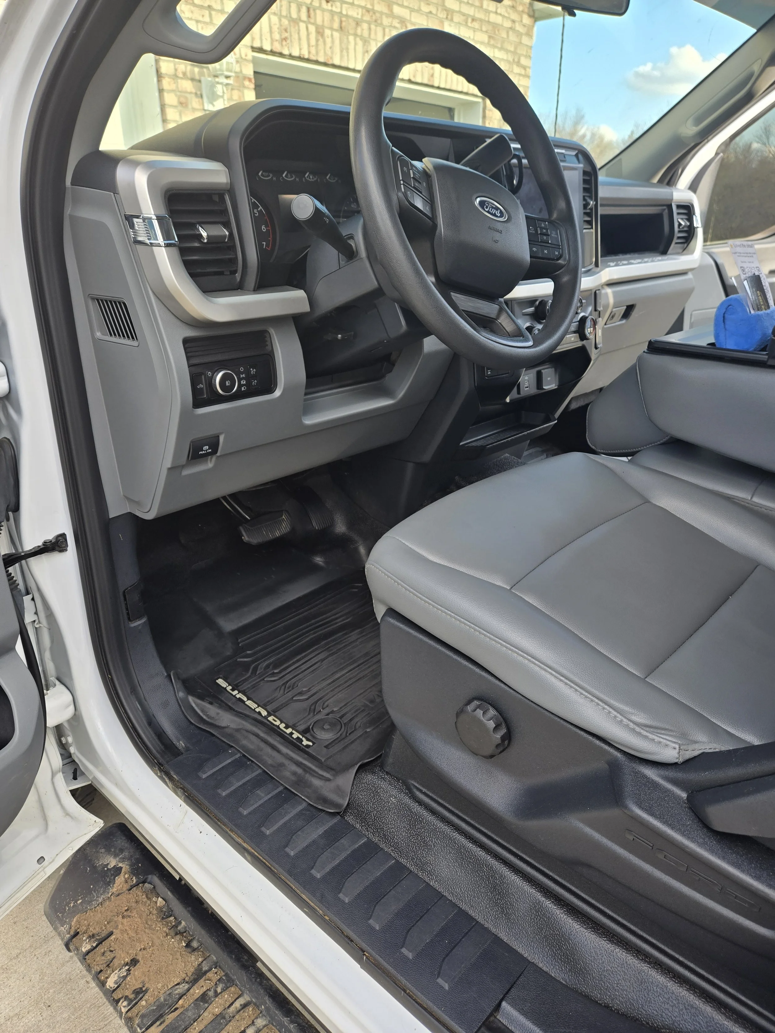 Interior of a Ford Super Duty truck, showing the steering wheel, dashboard, and driver's seat with a floor mat.