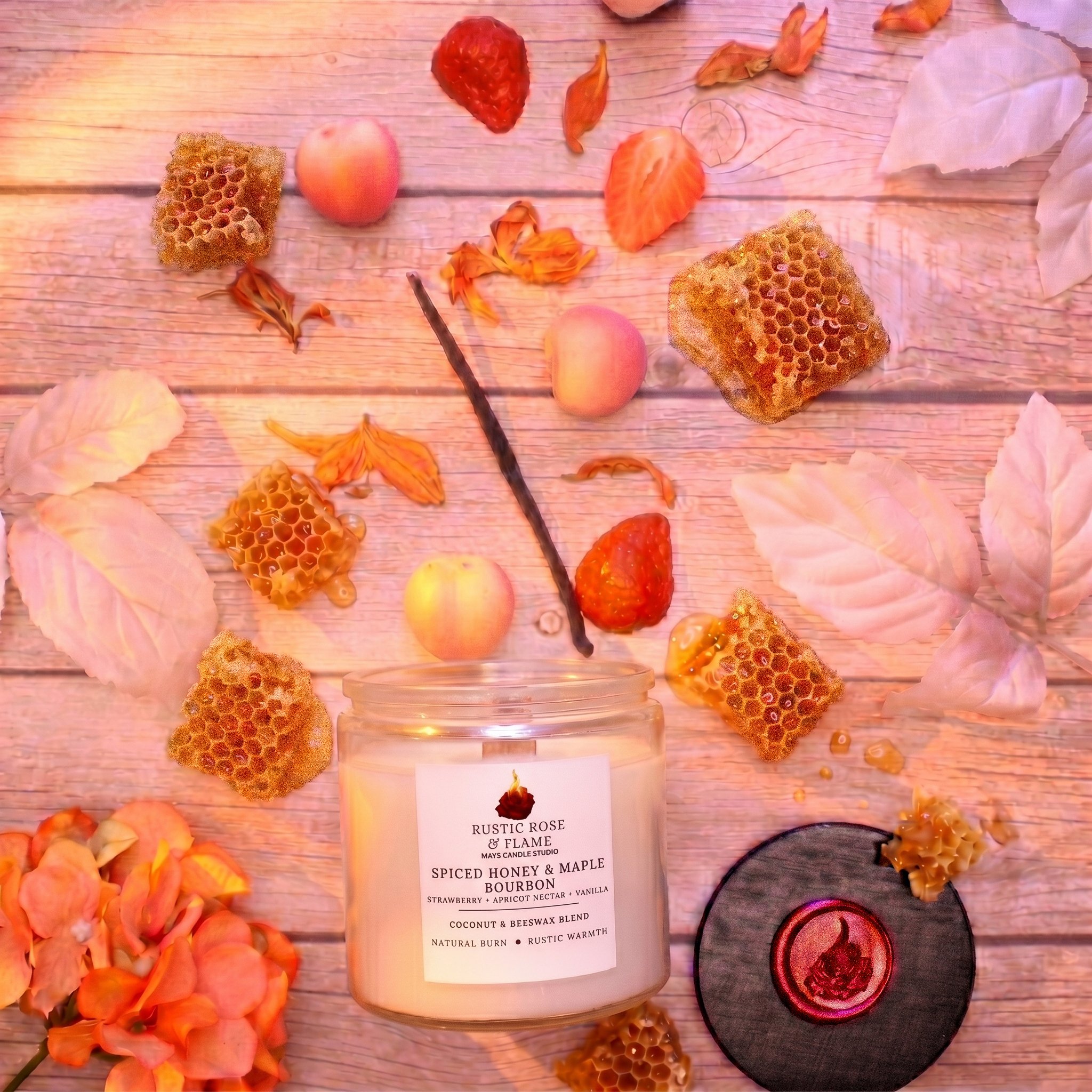 Arrangement of honeycomb, flower petals, strawberries, and candles on a wooden surface, with a candle label reading "Rustic Rose & Flame."