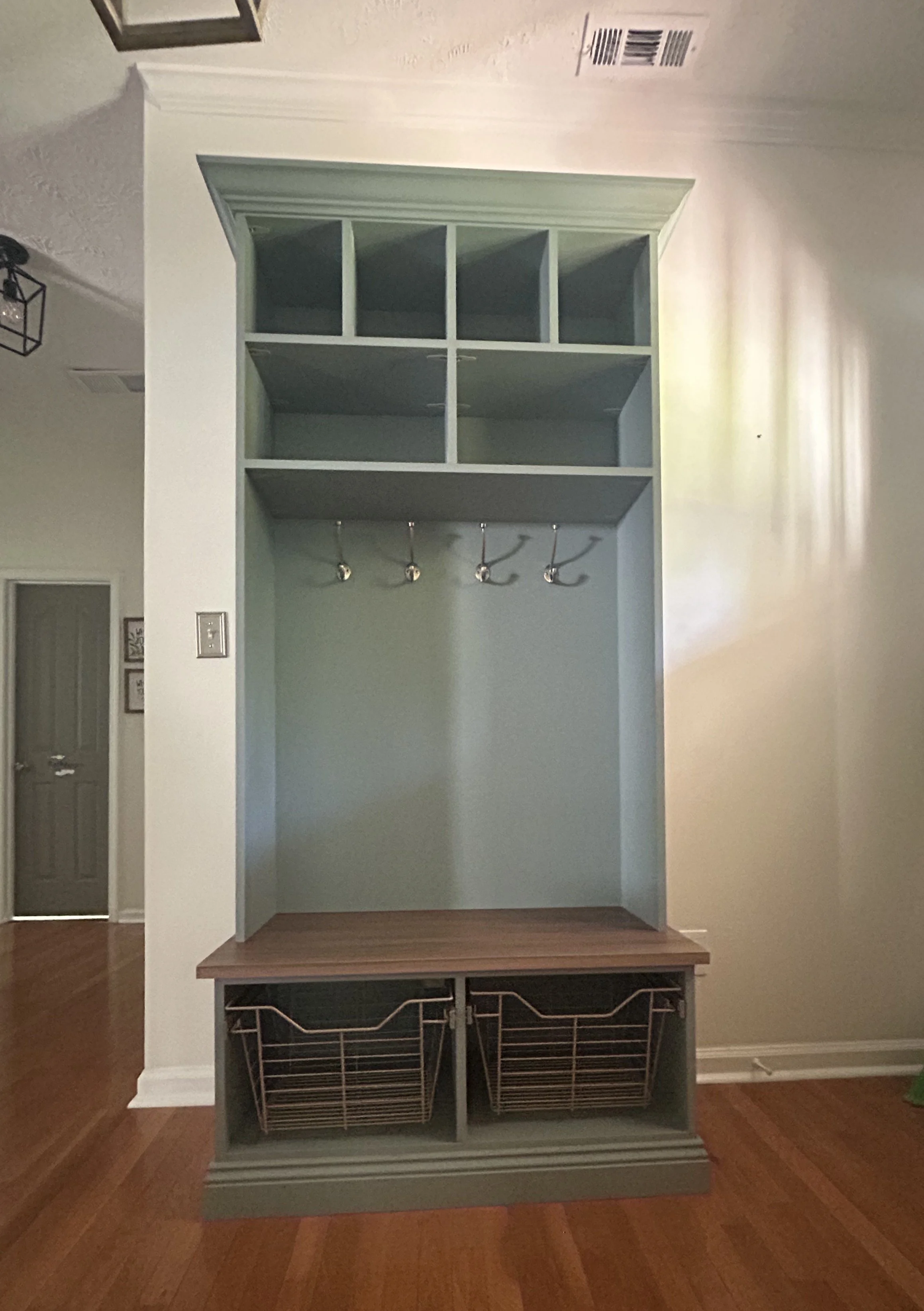 A custom built-in entryway Mudroom, with stored hooks and baskets for organizing shoes and accessories.