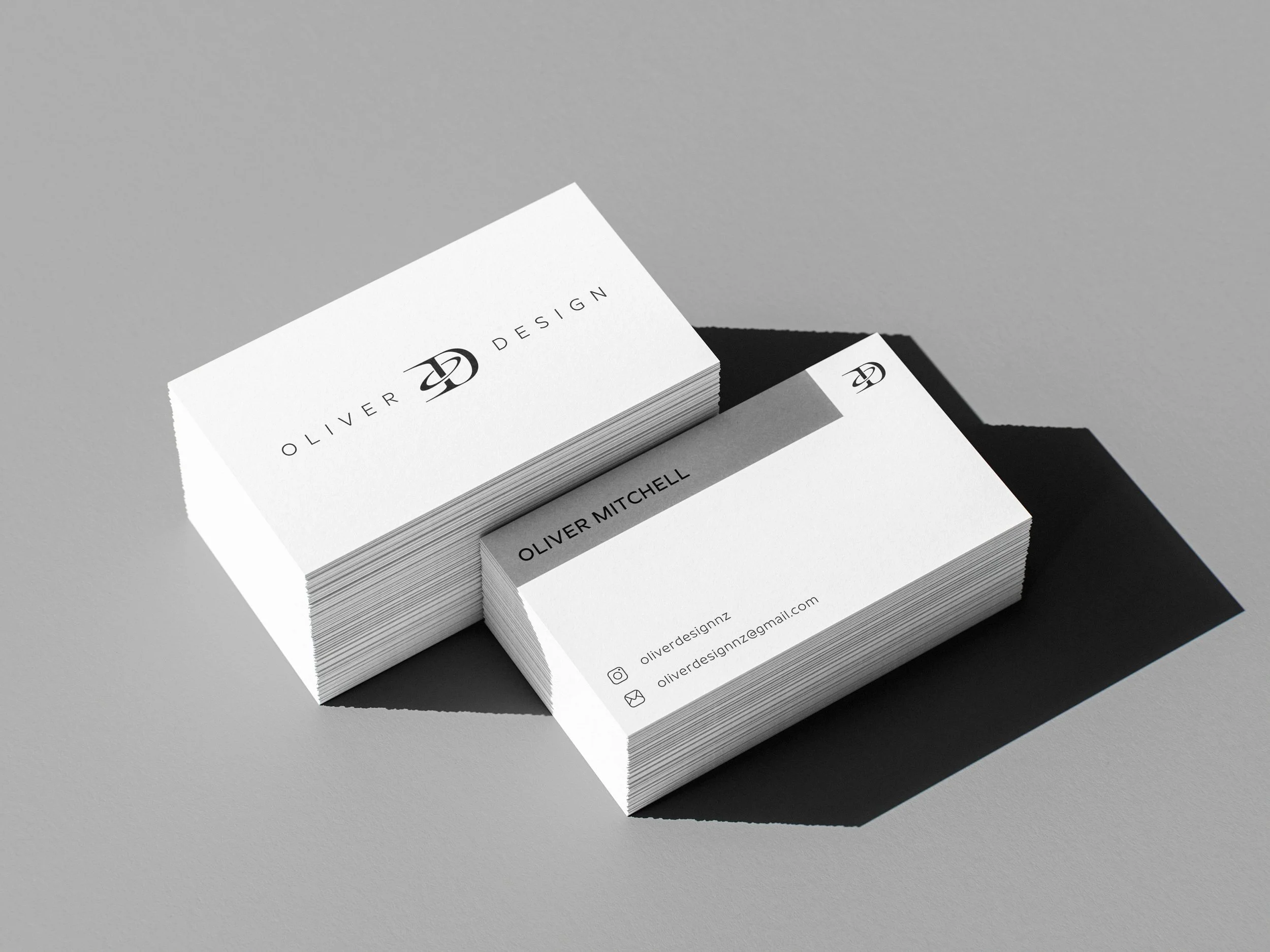 Stack of business cards for Oliver Design on gray surface, one card showing contact info and social media icons.