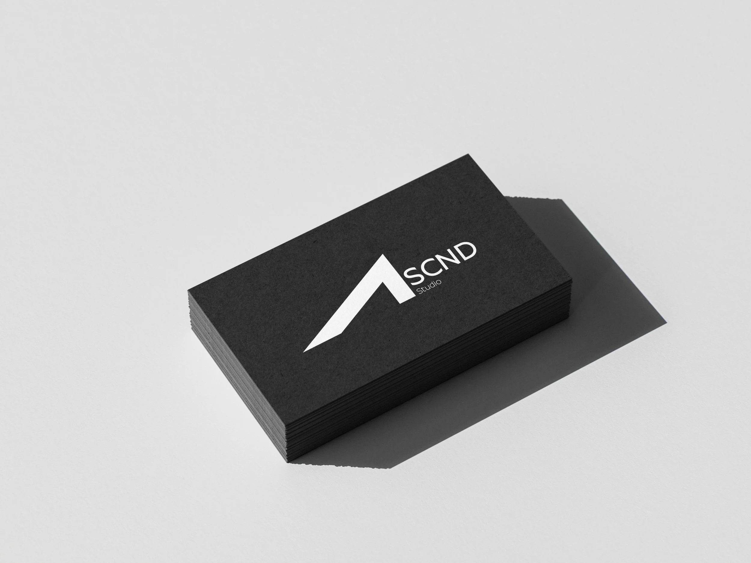 Stack of black business cards with a white logo and text reading 'S C N D Studio' on a white surface.