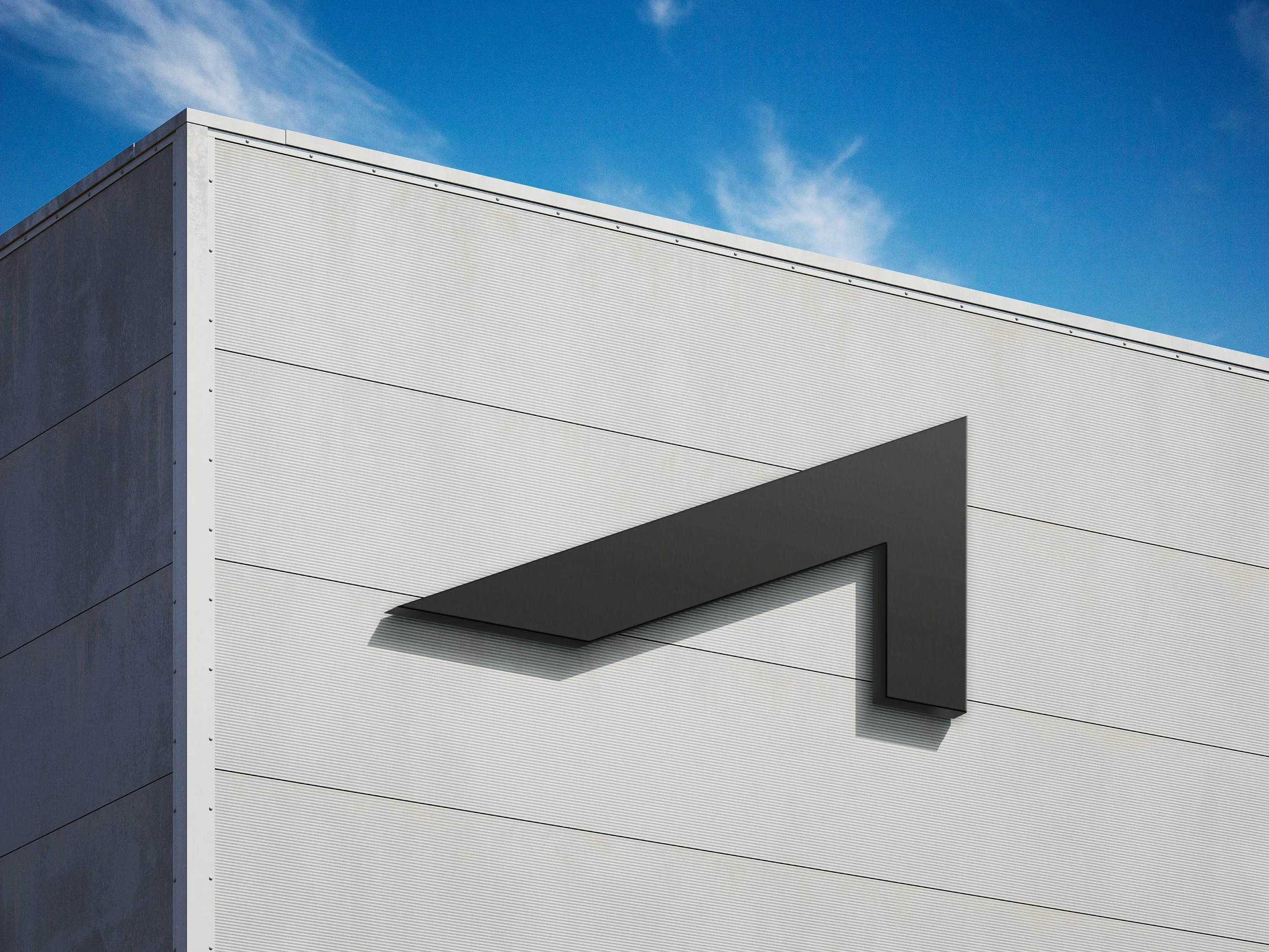 Close-up of a modern white building with a black angular architectural feature against a blue sky with some clouds.
