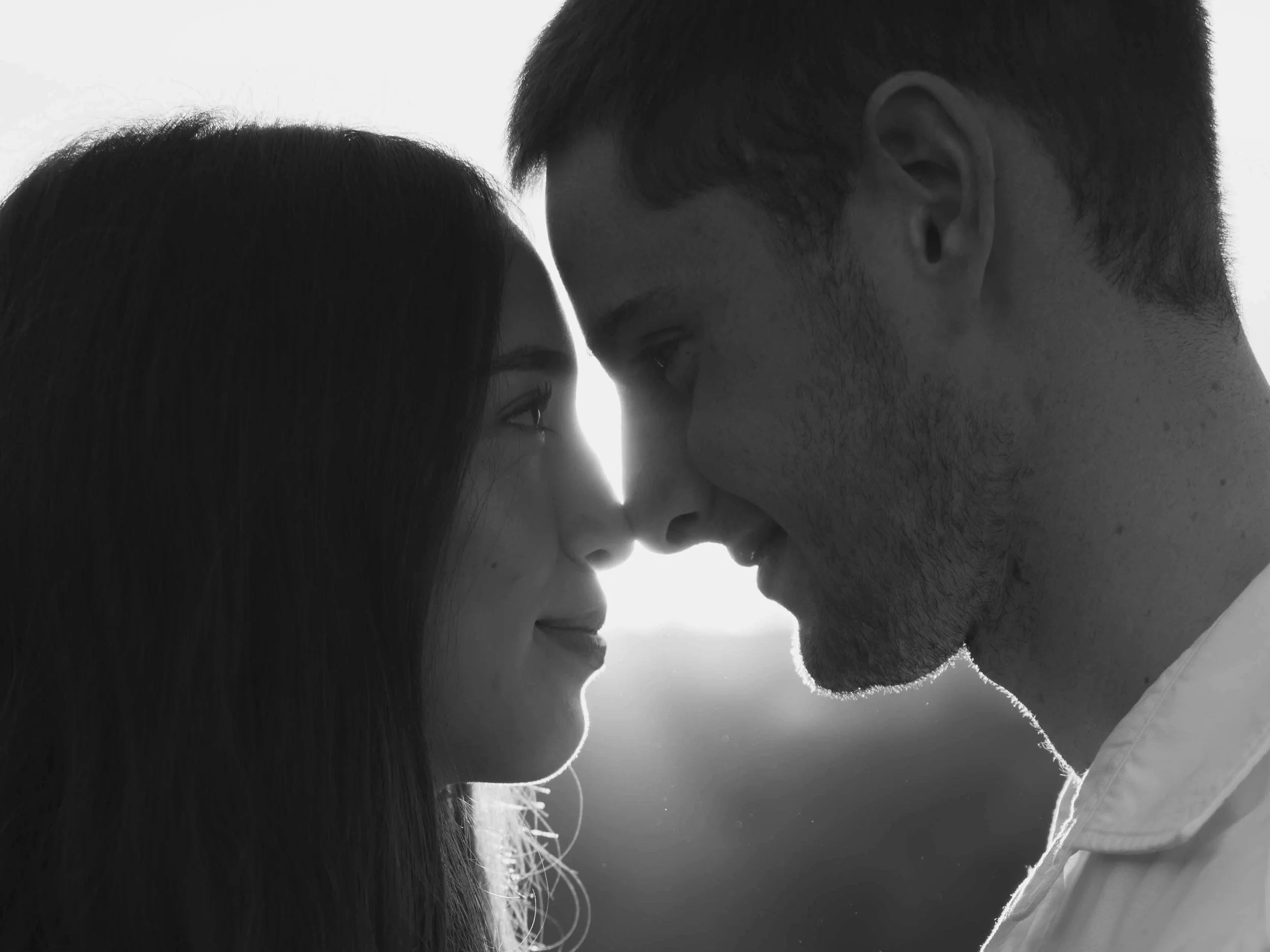 Black and white photo of a young couple with foreheads touching, gazing into each other's eyes, close together.
