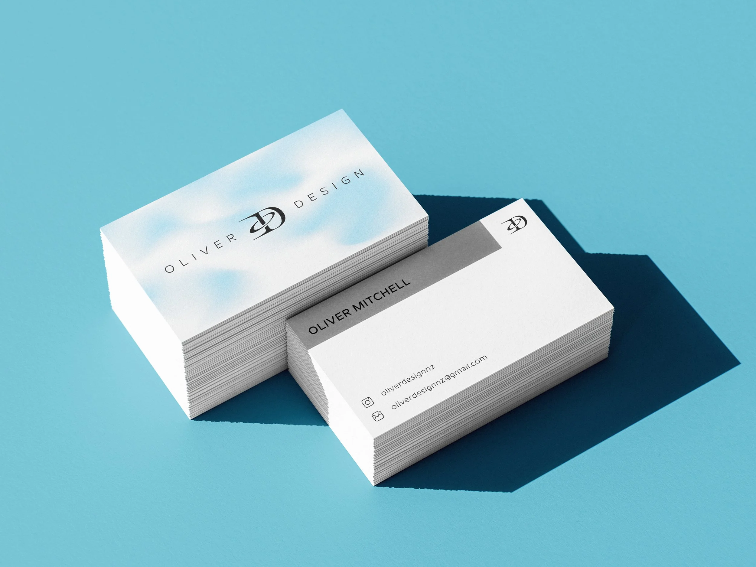 Stack of business cards for Oliver Design on a blue background, with one card showing social media and email contact information.