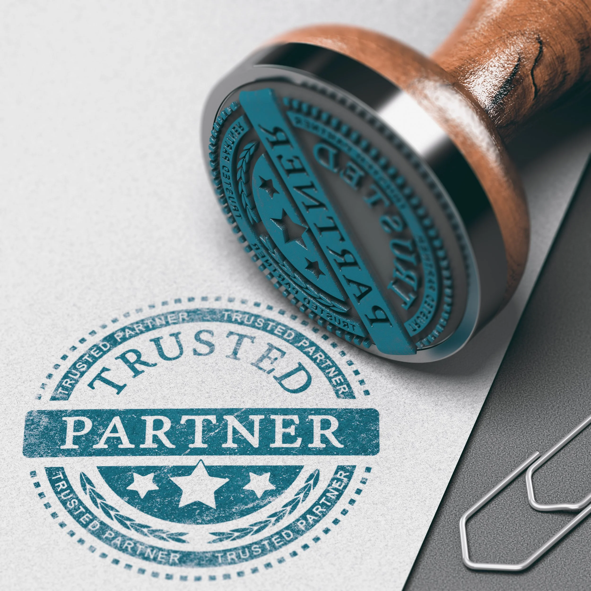 A blue rubber stamp presses onto a white paper, imprinting a circular trust partnership badge with stars and laurel leaves.