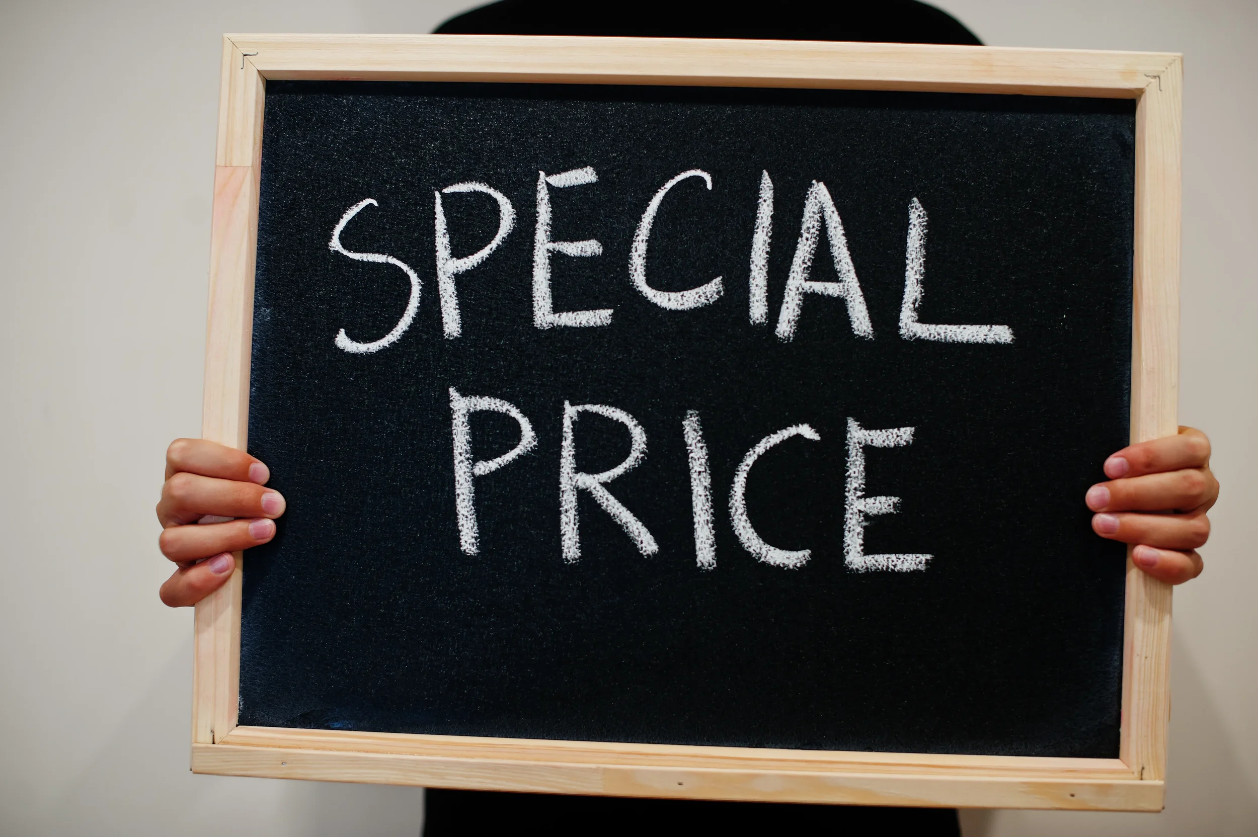 A person holding a black chalkboard with a wooden frame that has 'SPECIAL PRICE' written in white chalk.