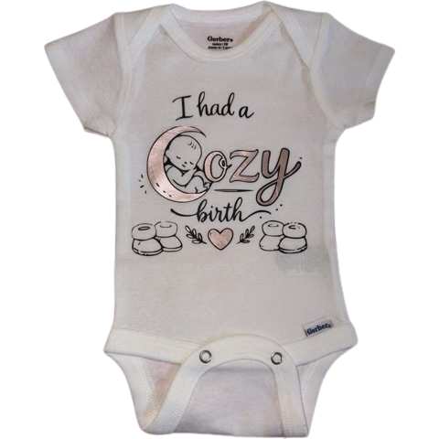 White baby onesie with the text "I had a cozy birth" and illustrations of a crescent moon with a sleeping baby, cookies, and a heart.
