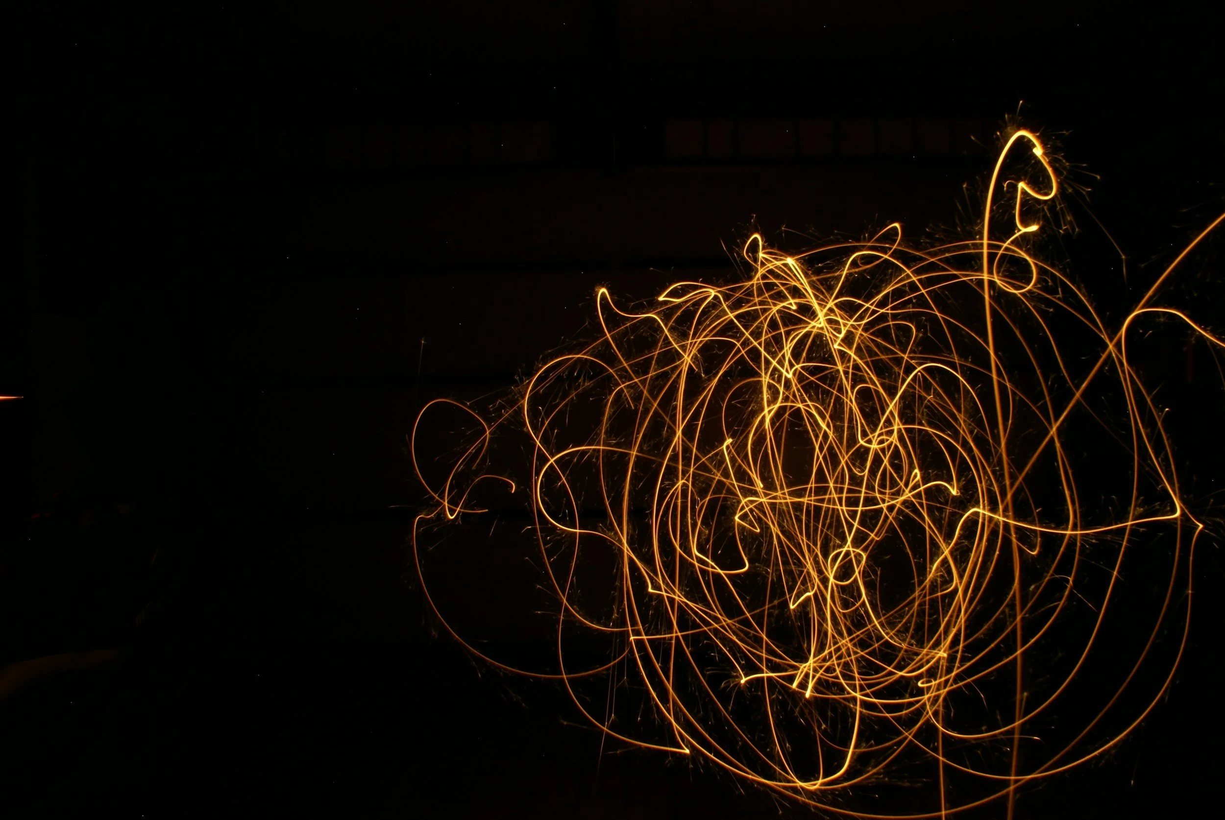 Light trails created by sparklers against a dark background.