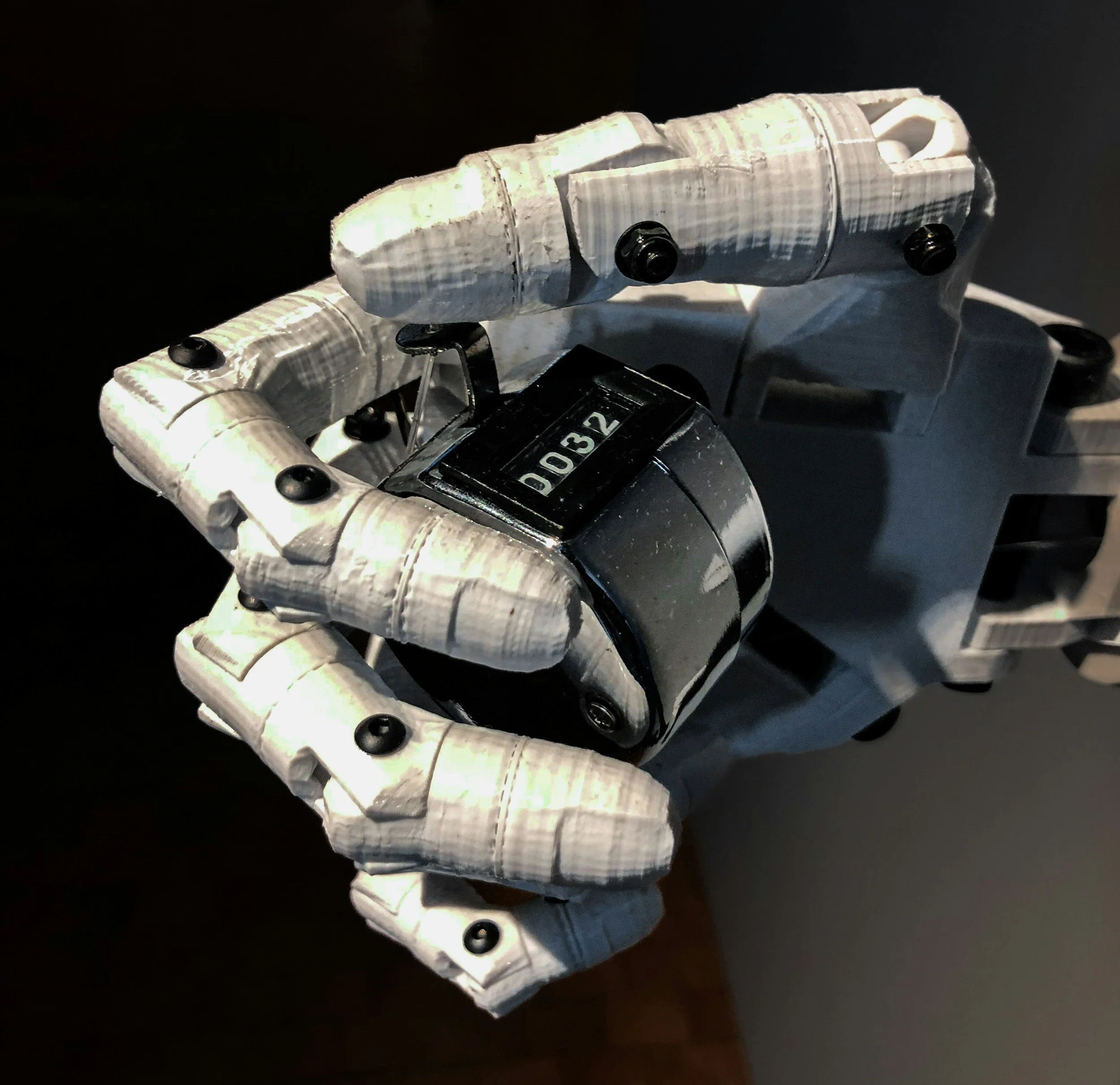 A robotic hand holding a black and white mechanical counter showing the number 032.