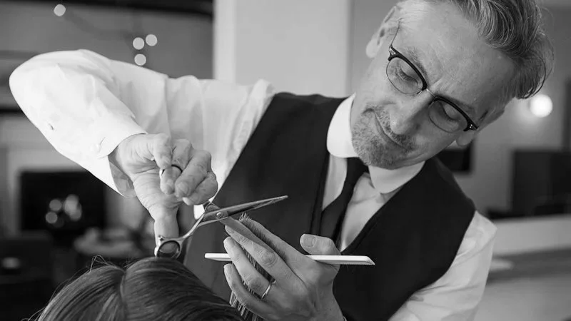 A hairstylist cutting a person's hair in a salon.