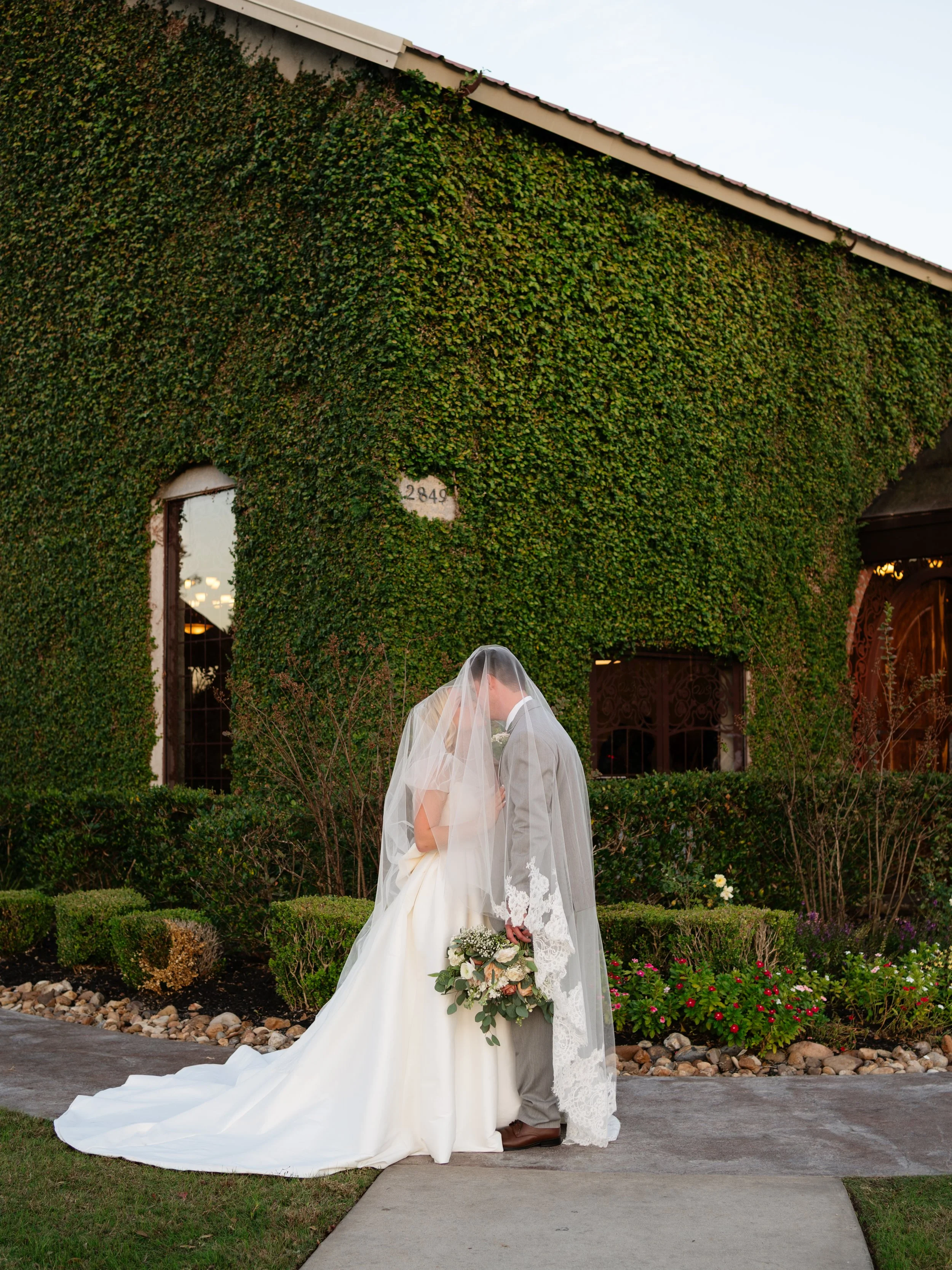 A romantic bridal portrait set against an ivy-covered wall in Montgomery, TX, showcasing soft movement and timeless elegance.