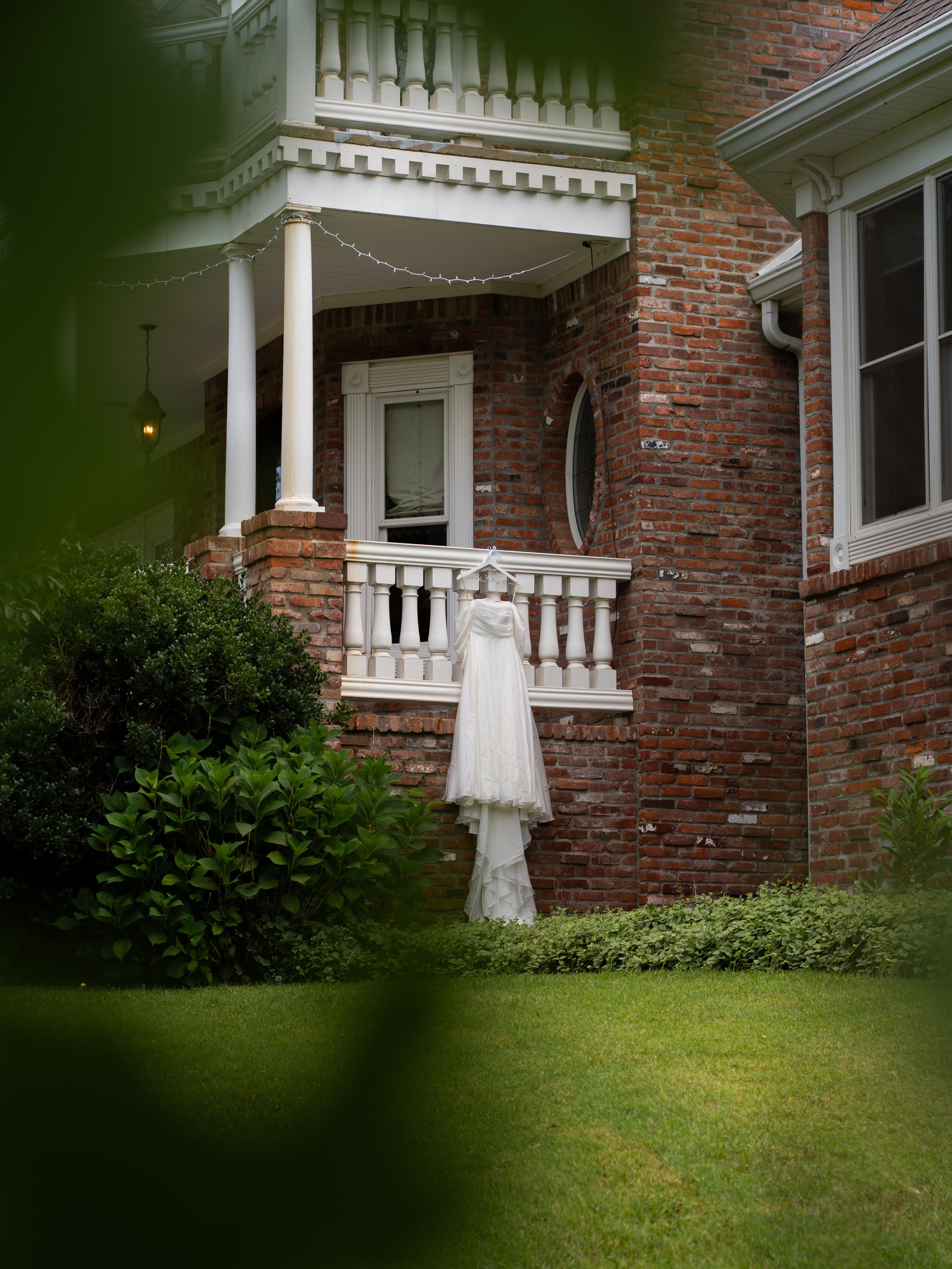 Wedding Dress hung on the house surrounded by greenery 