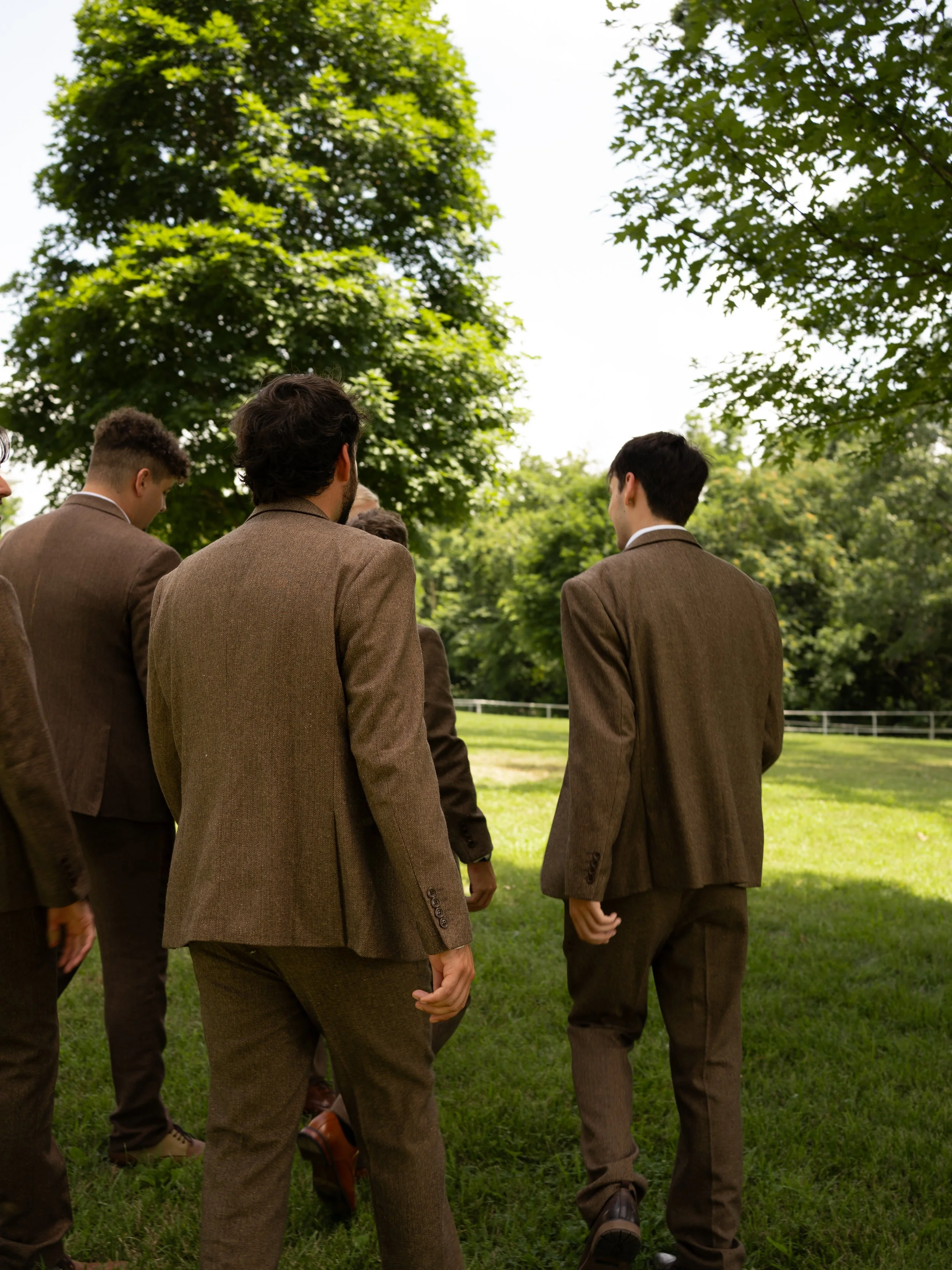 Groomsmen walking in green field