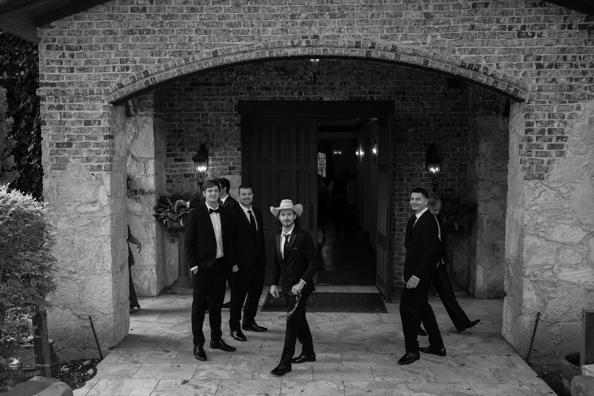 A classic black-and-white portrait of the groomsmen in Waxahachie, Texas, capturing movement and timeless style.