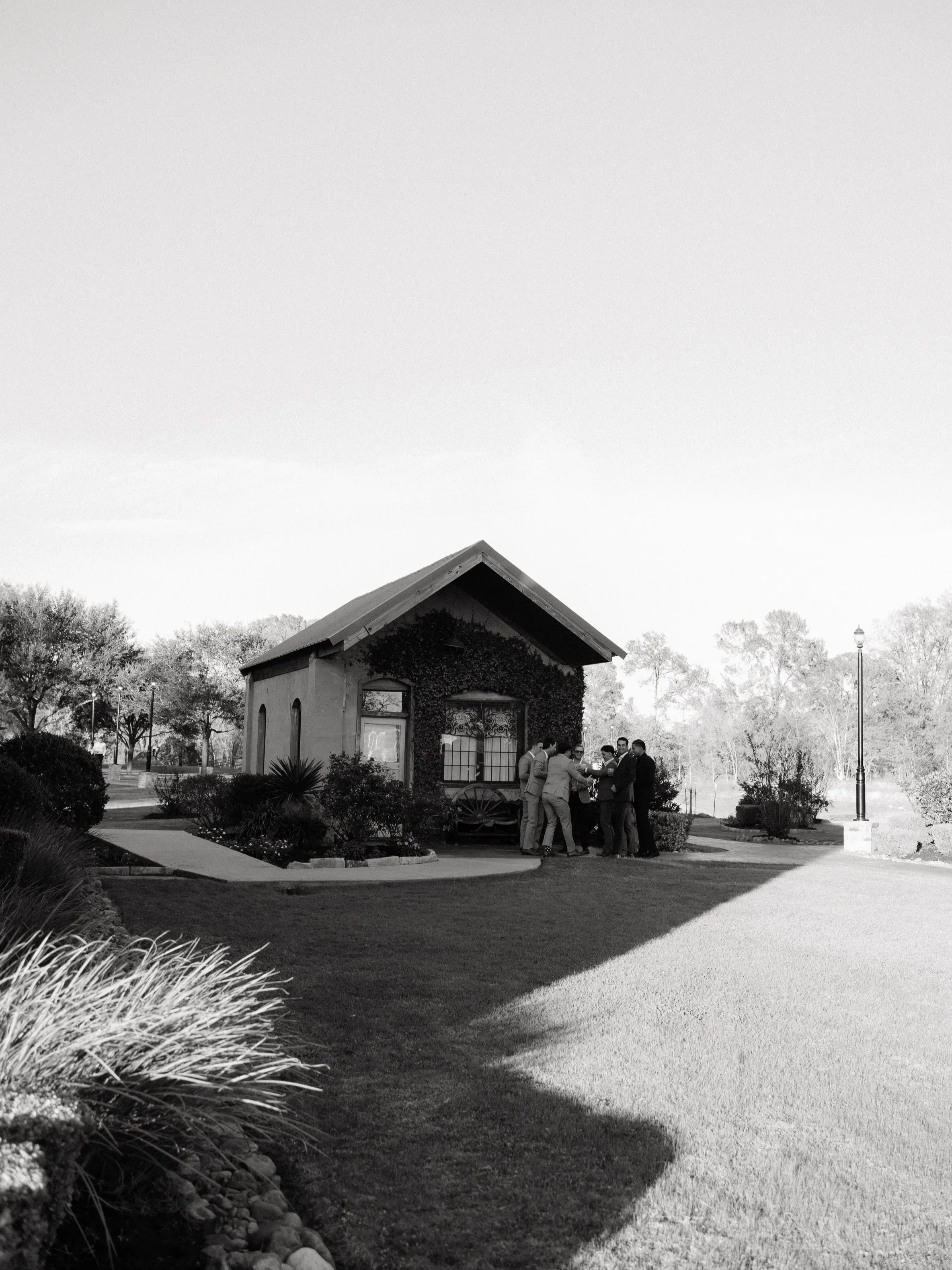 A wide black-and-white view of a Montgomery, Texas wedding venue, emphasizing natural surroundings and timeless architectural character.