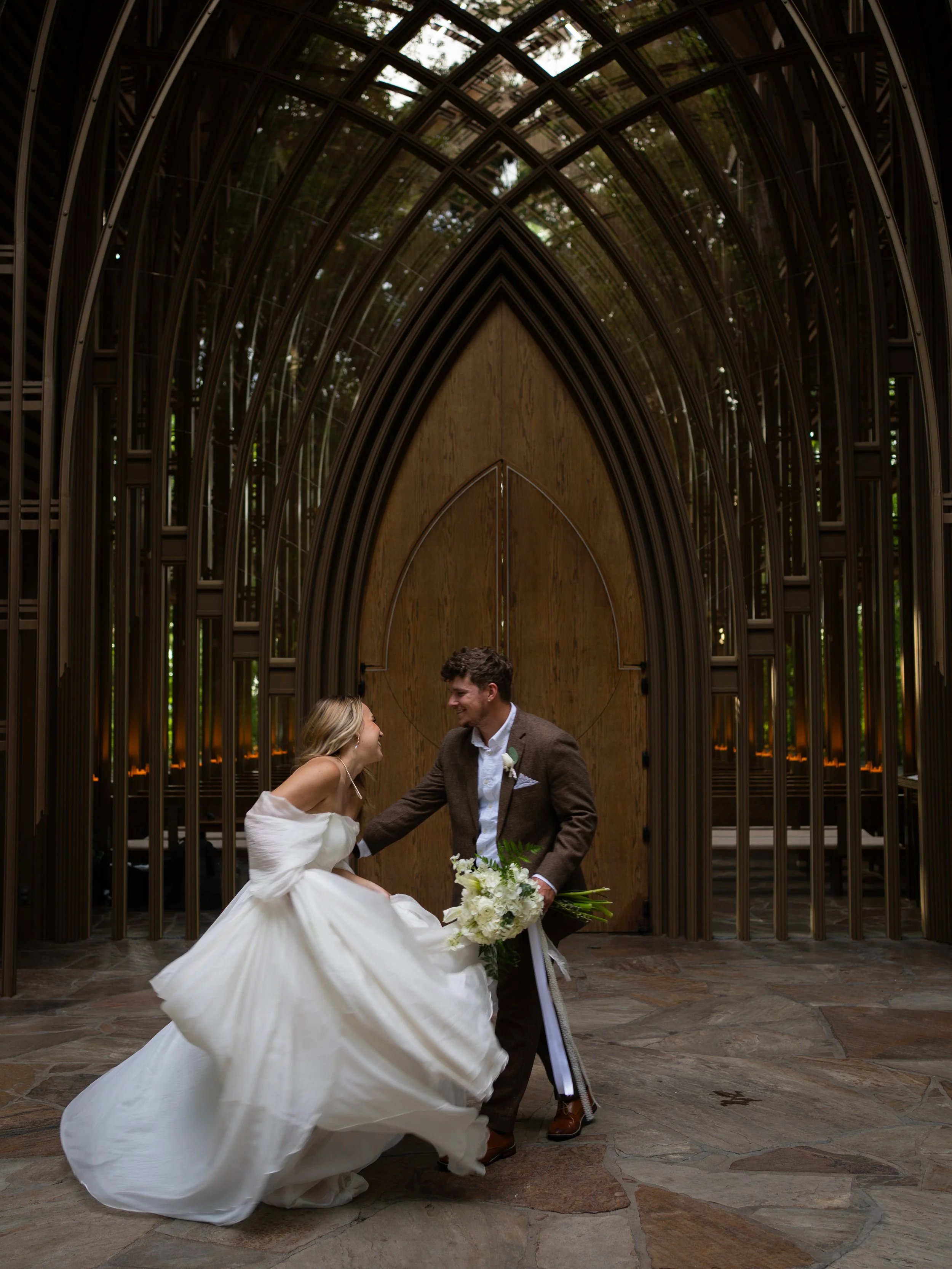 Bride and groom portraits laughing and dancing outside Mildred B Cooper Memorial Chapel in Bella Vista, Arkansas