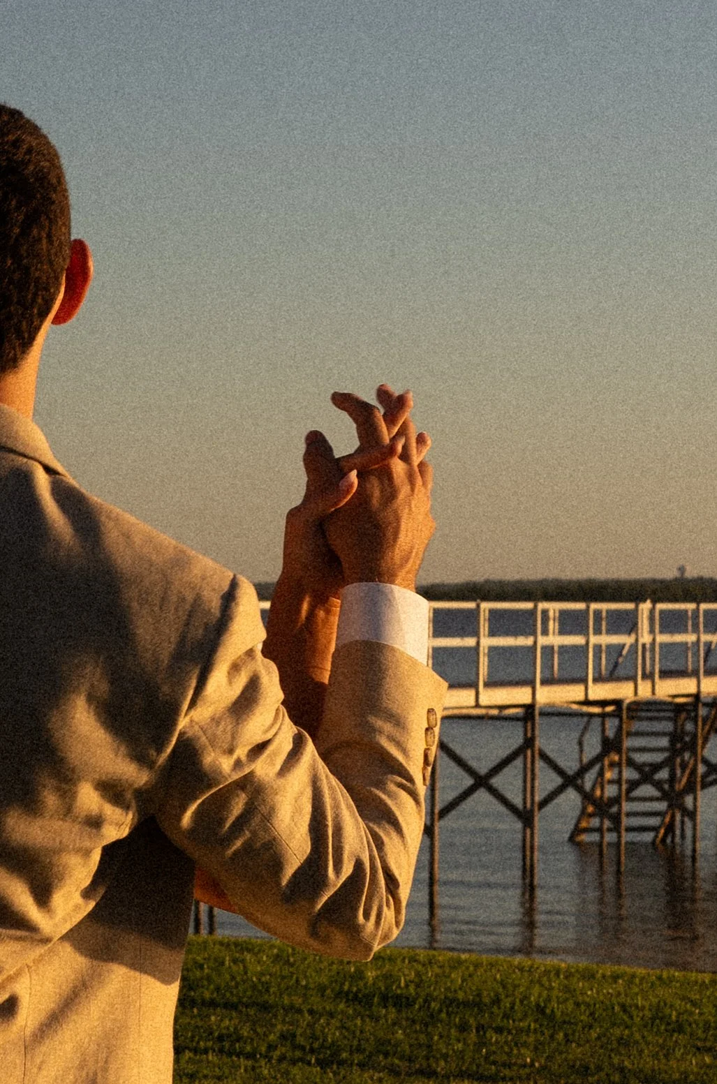 Bride and groom holding hands detail shot by the lake house dock