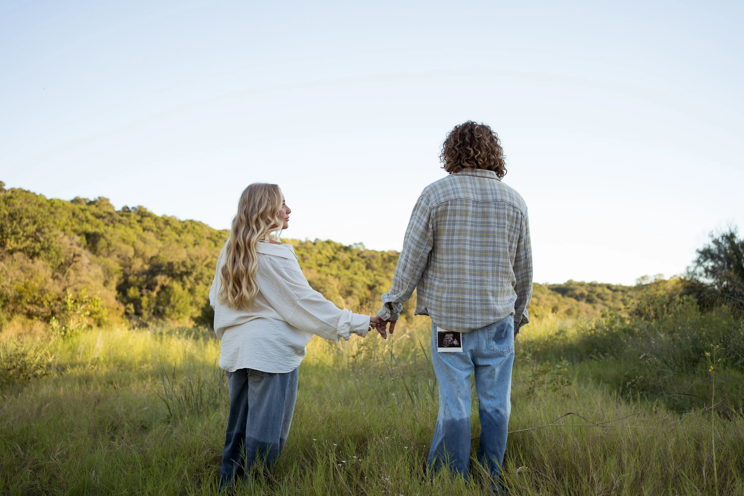 A peaceful moment in Rainbow, Texas, as the couple walks hand in hand through an open landscape.