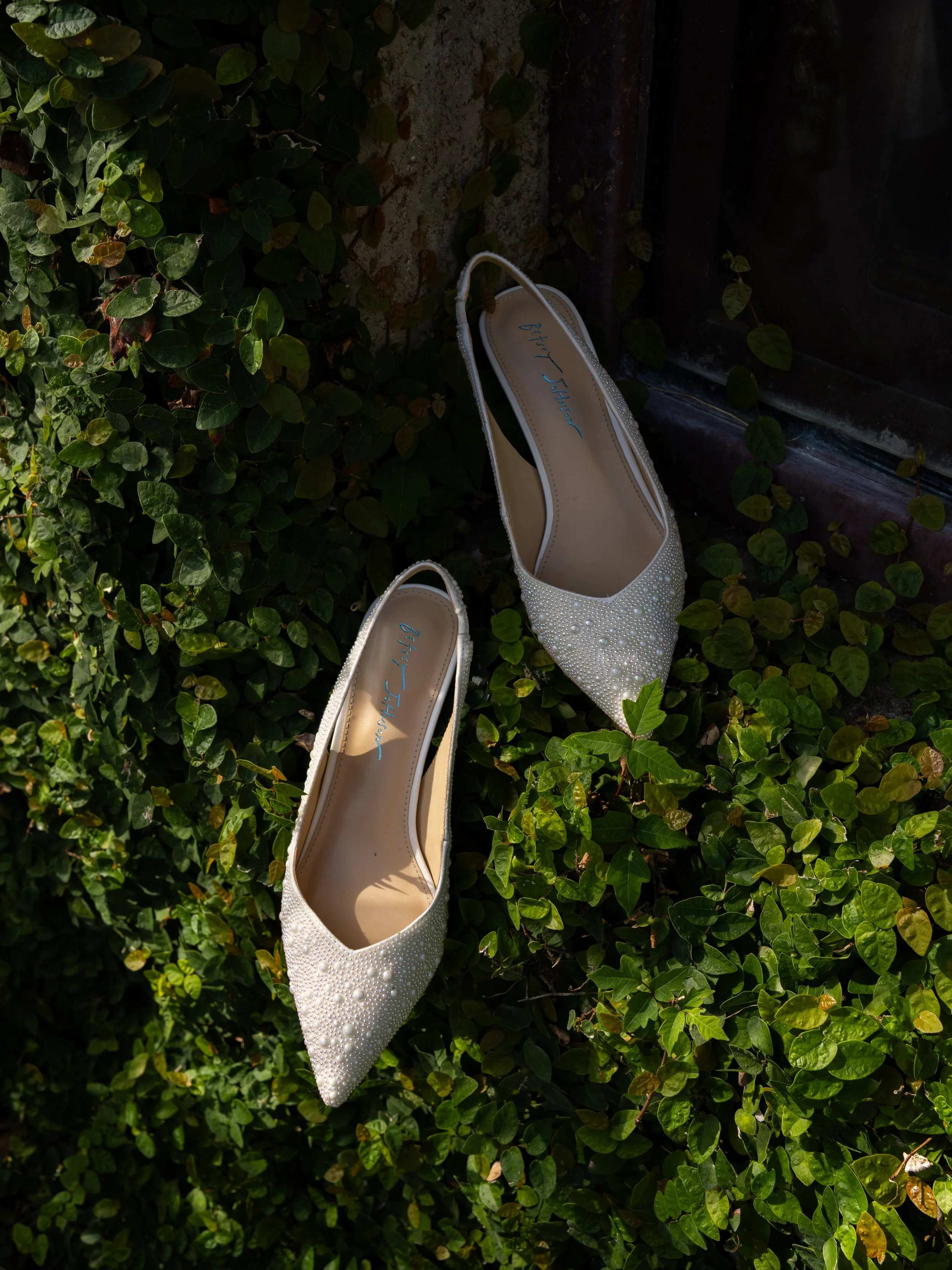 Elegant bridal details styled outdoors in Montgomery, TX, featuring classic wedding shoes nestled in lush greenery for a refined and organic aesthetic.