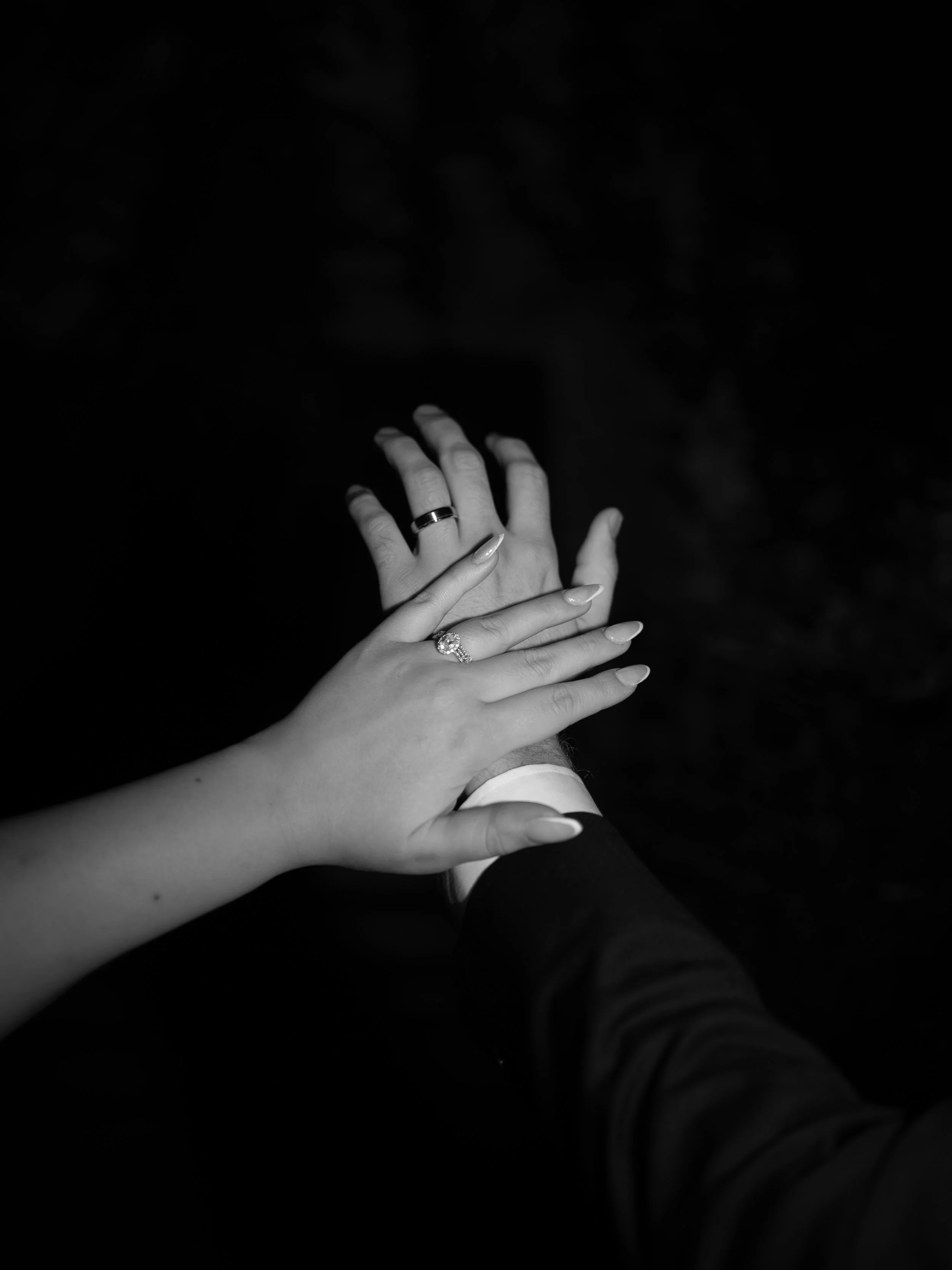 A minimalist black-and-white detail in Waxahachie, TX, highlighting the couple’s hands and wedding rings.