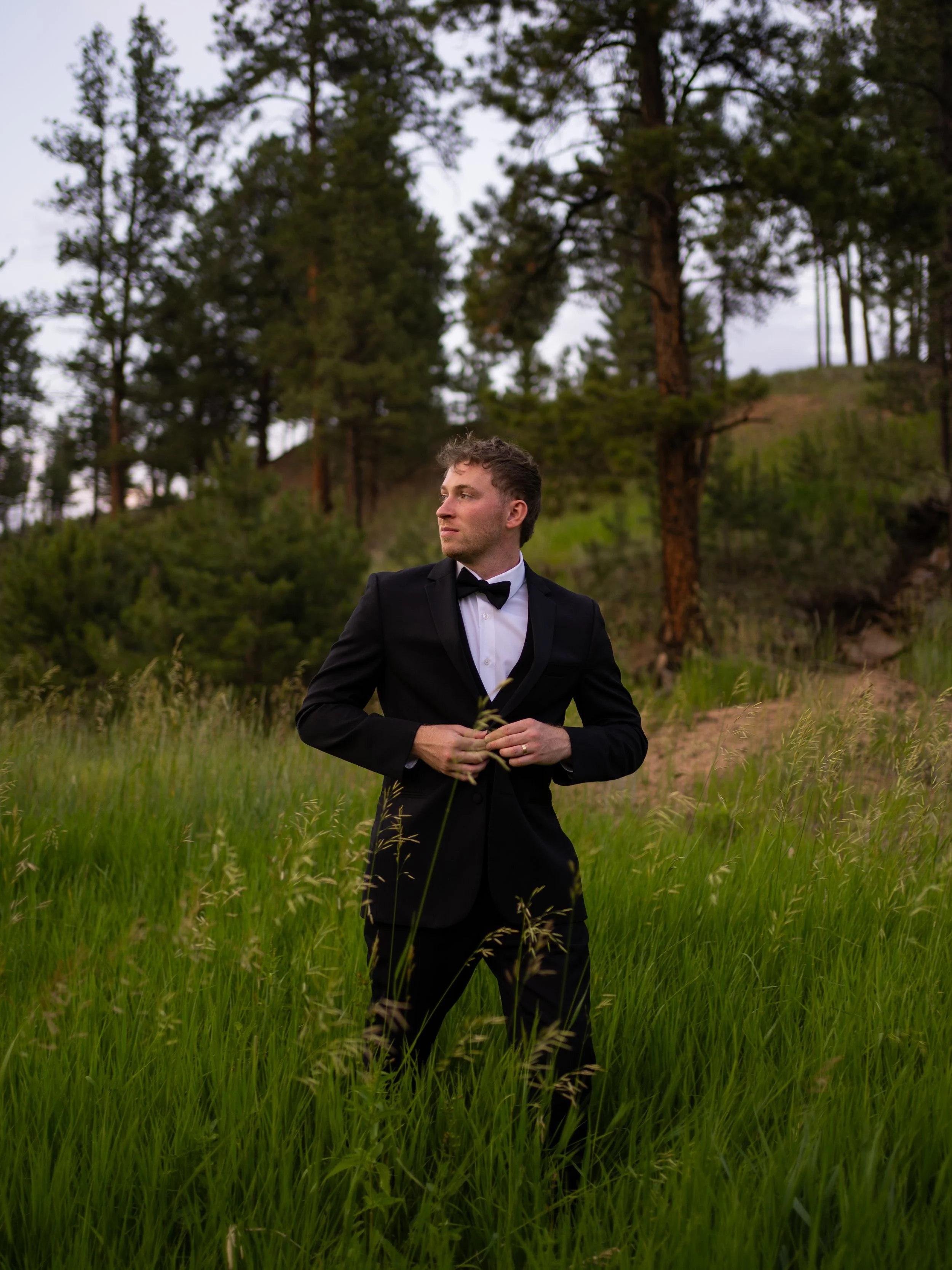 An editorial-style groom portrait in Woodland Park, CO, set against a natural landscape with soft evening light.