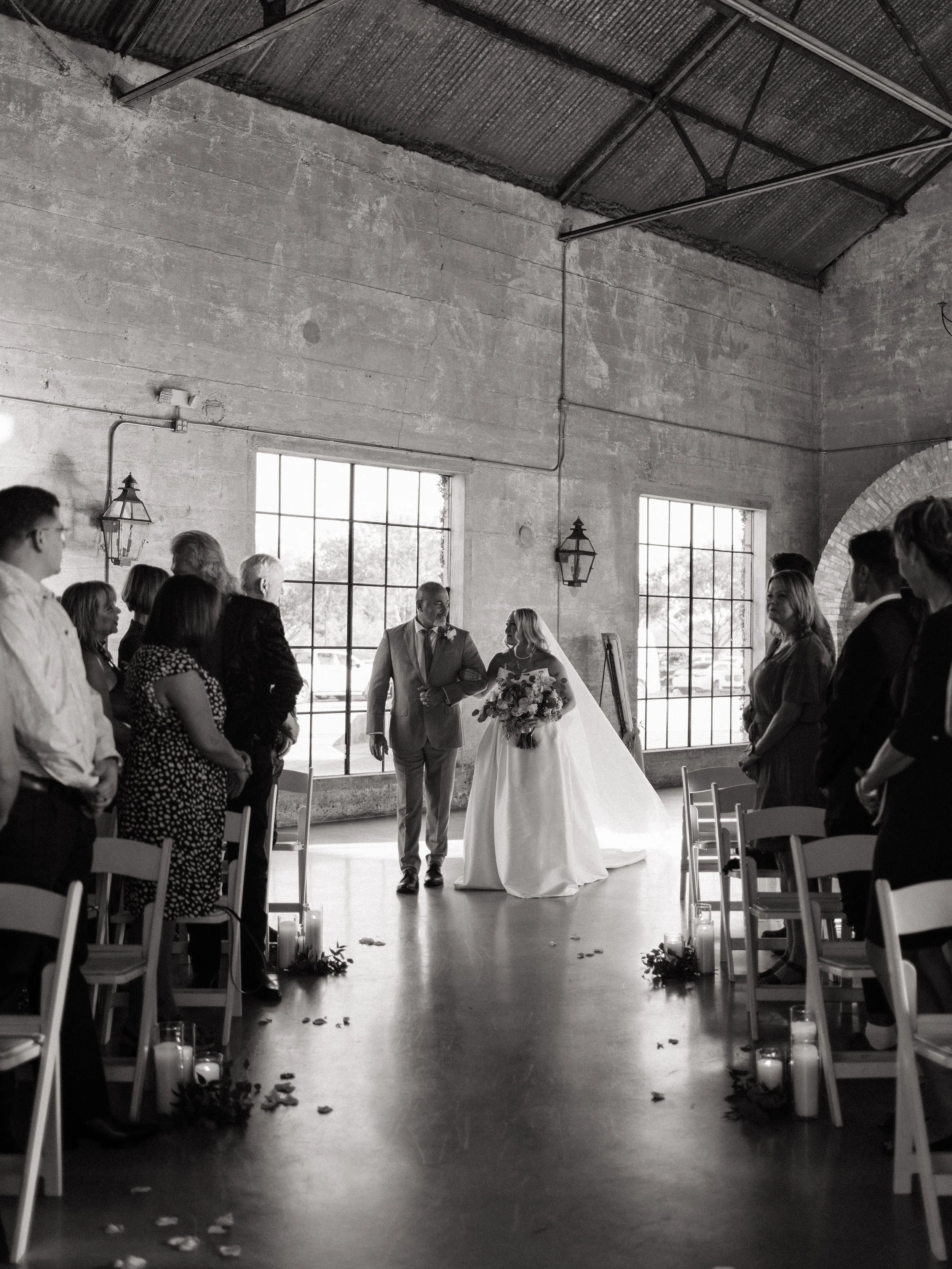 A documentary-style black-and-white image of the bride entering the ceremony in Montgomery, TX, capturing anticipation and stillness.