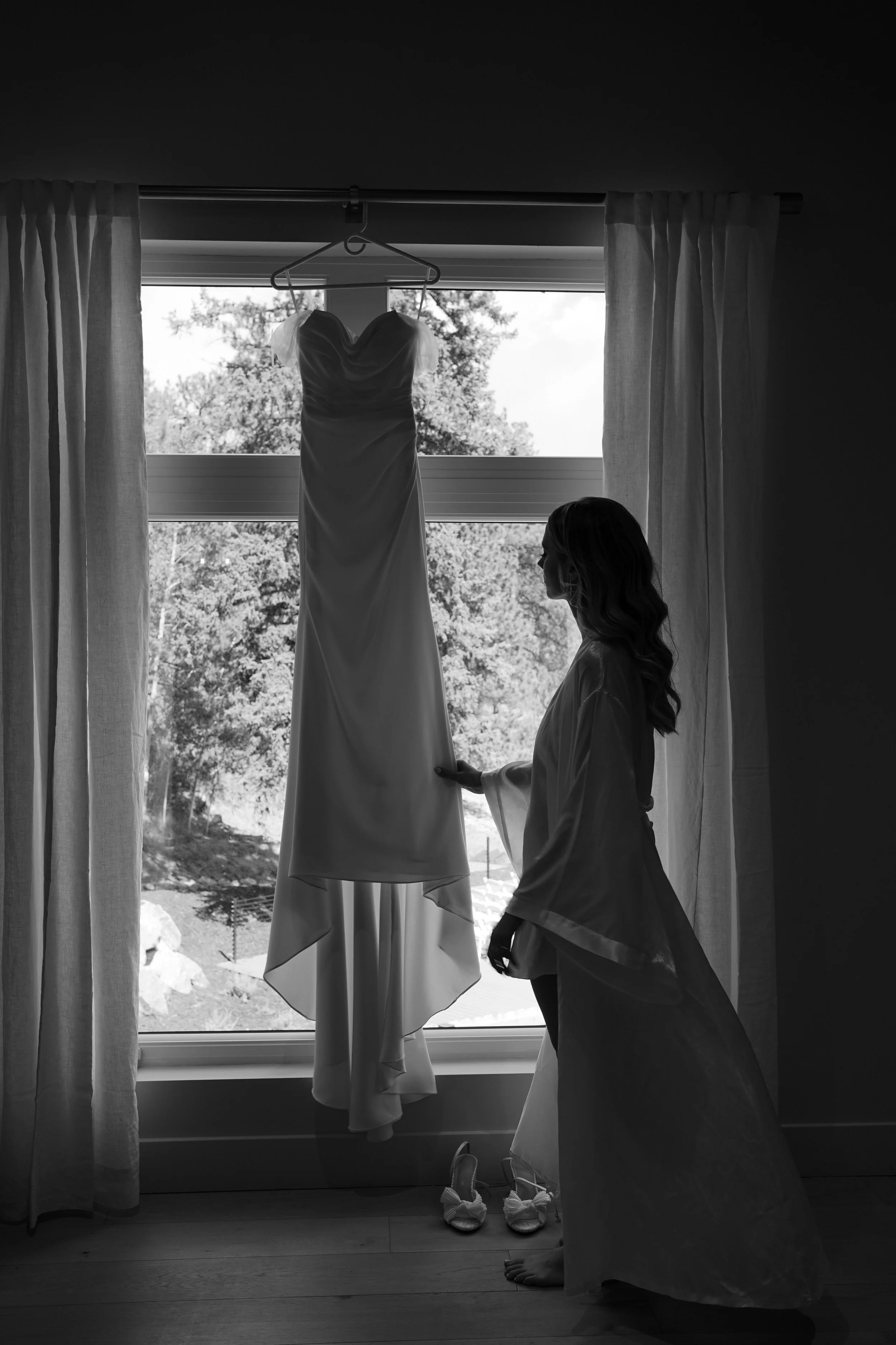 Moody black and white silhouette of the bride by a window during quiet getting ready moments in Pine, Colorado.