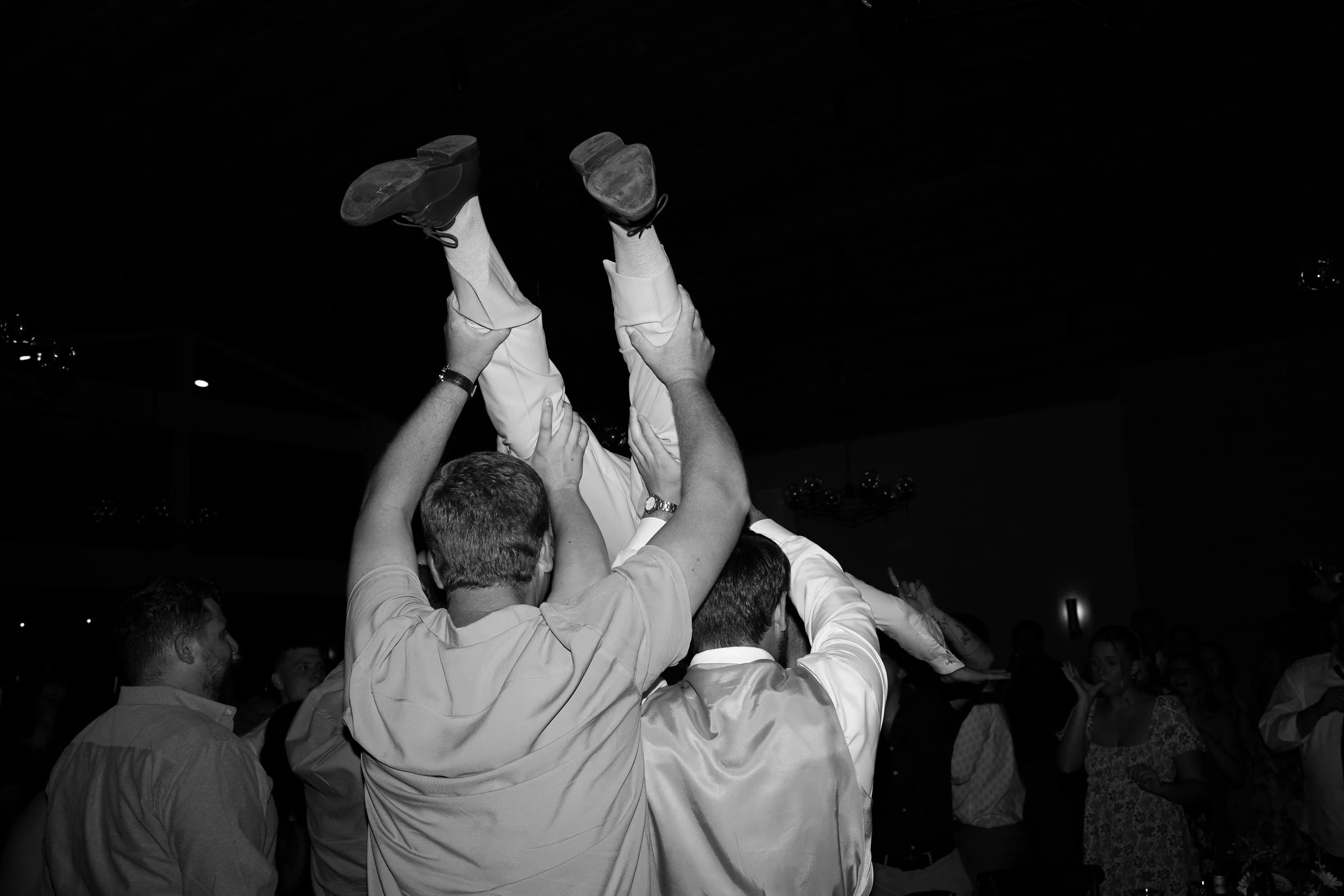 Candid dancing reception of the groom lifted in the air during a lively wedding celebration in Pine, Colorado.