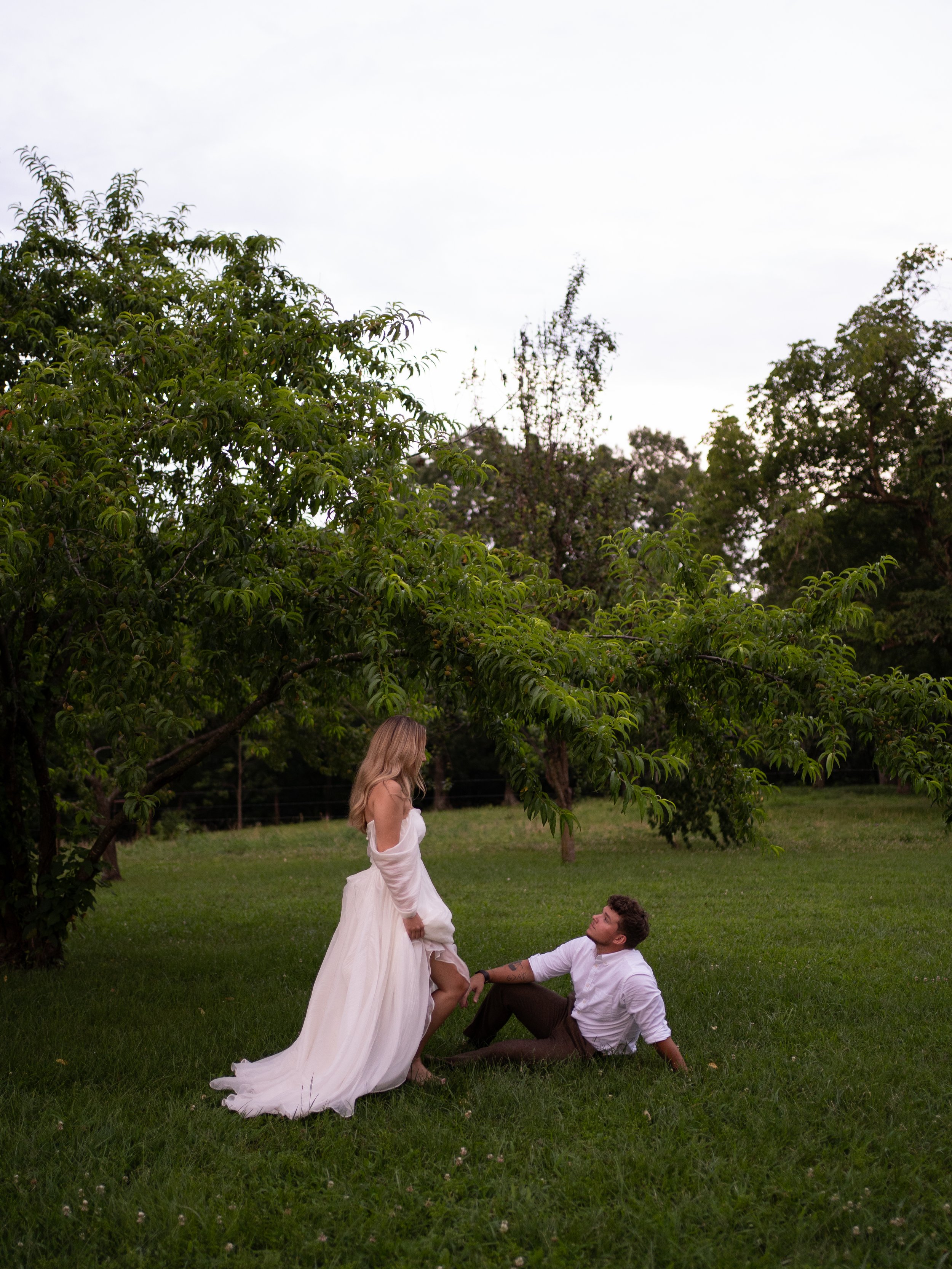Bride and groom sitting and standing together in a field