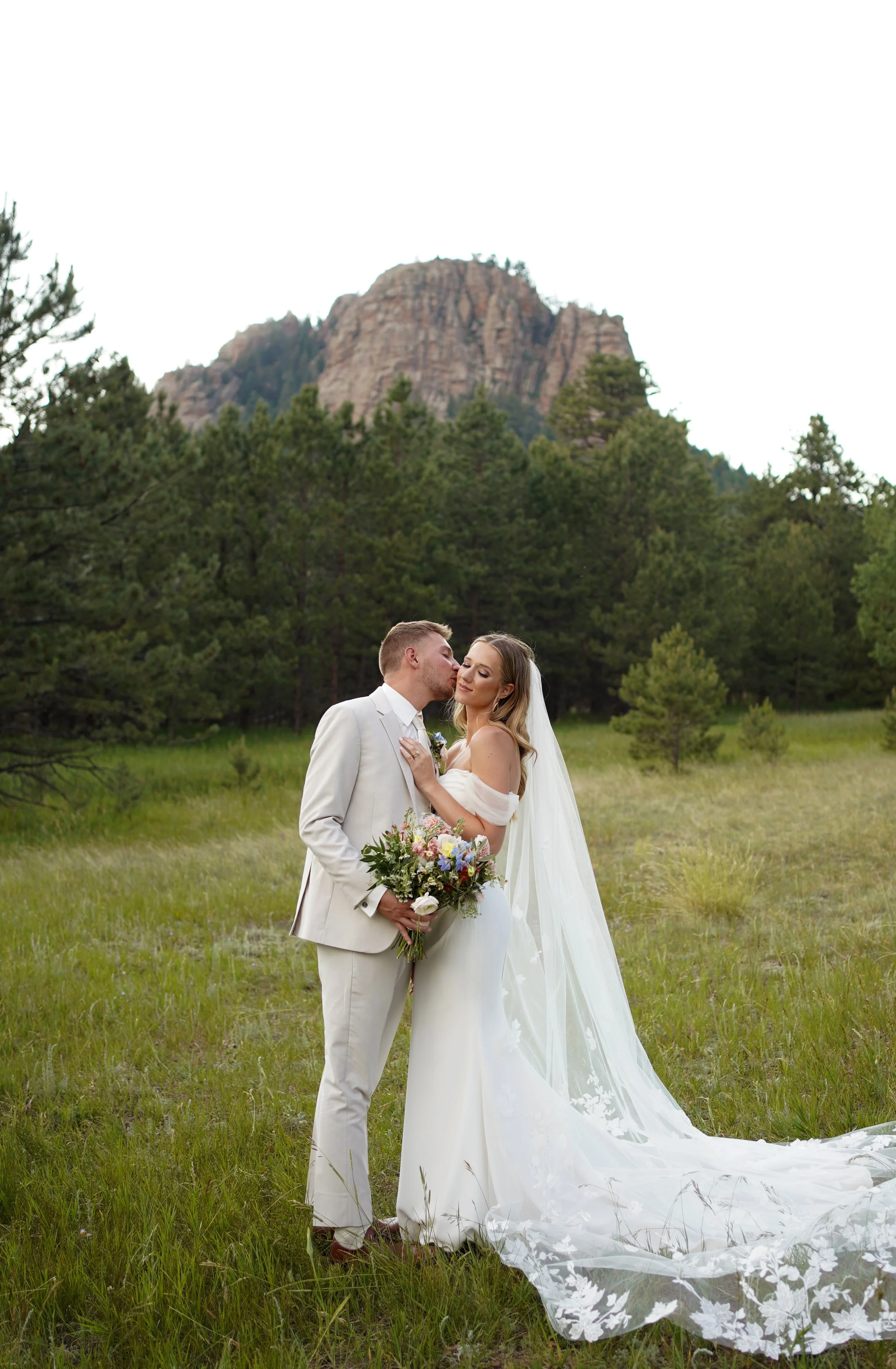 Romantic couple portrait in an open field with mountain views during a wedding in Pine, Colorado.