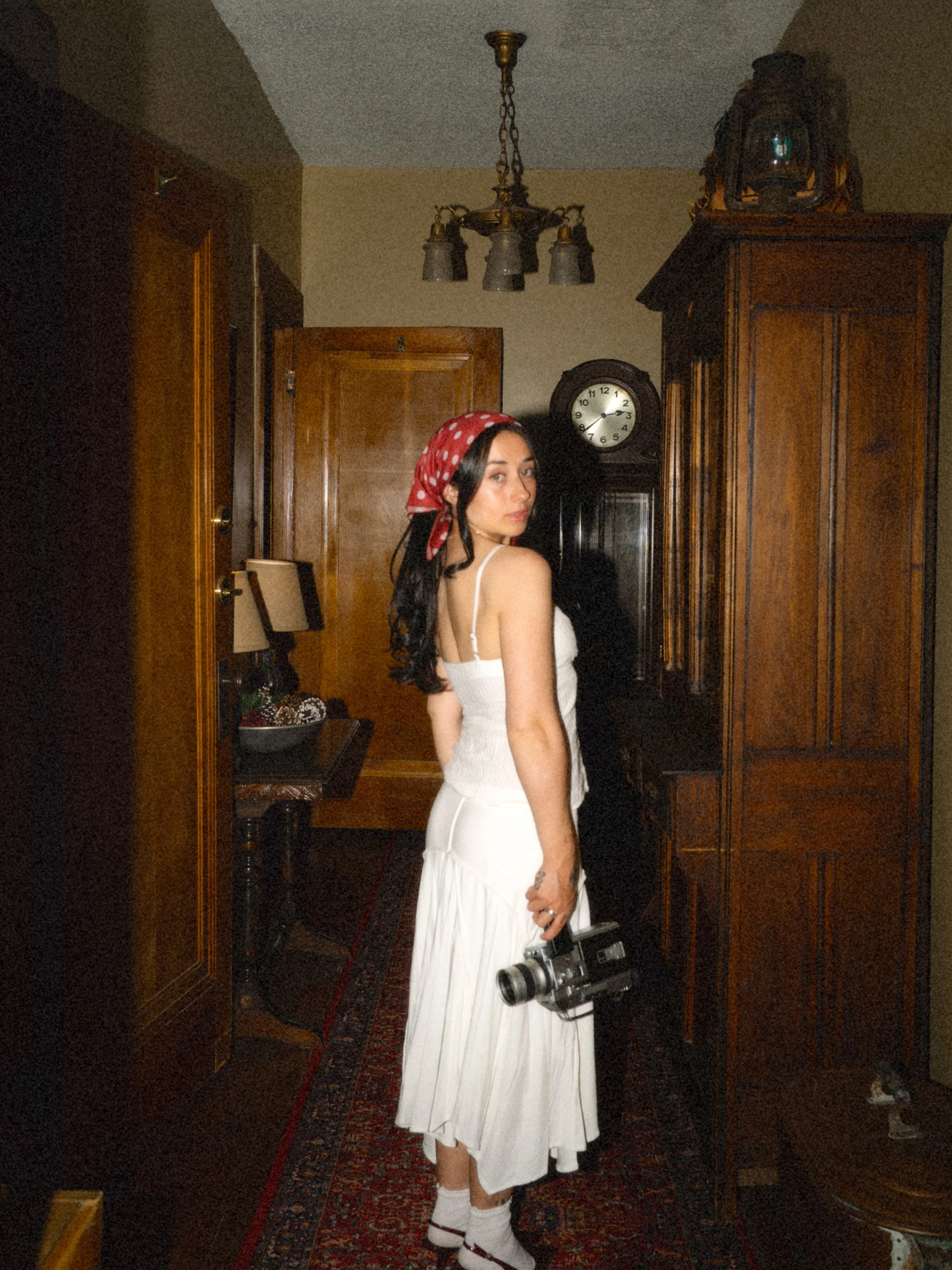 Wedding photographer and videographer holding a film camera in a warmly lit room, turning back toward the light