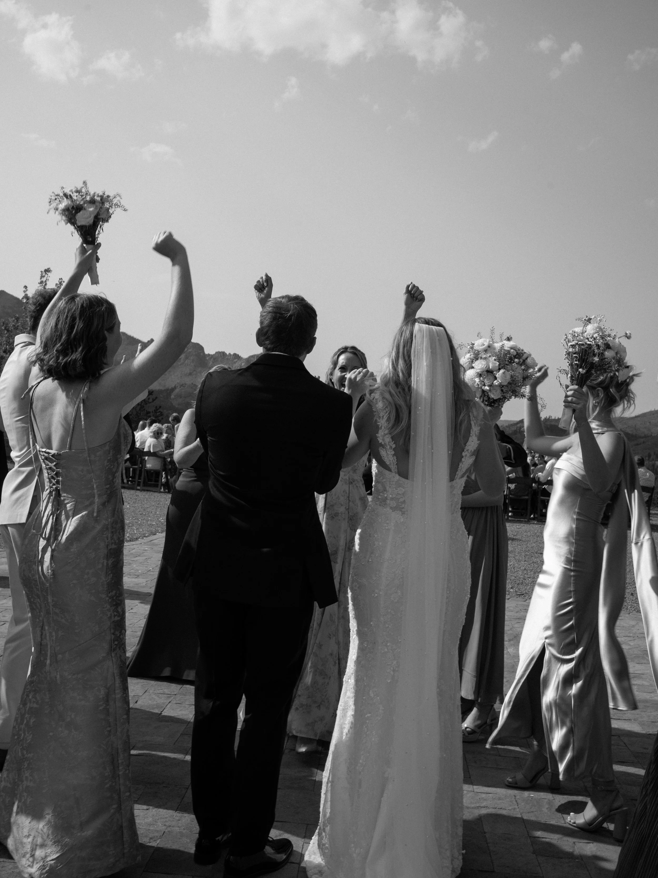 A joyful black-and-white ceremony exit at Pikes Peak Ranch in Woodland Park, Colorado, capturing celebration and movement.