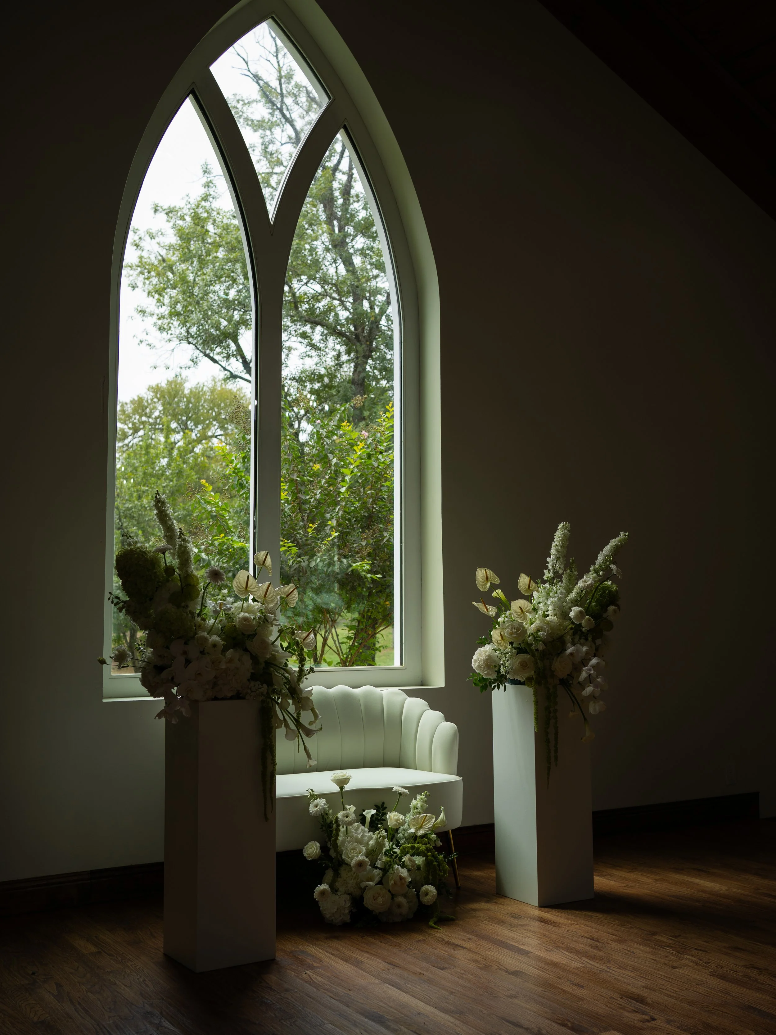 A refined ceremony setup in Waxahachie, Texas, featuring soft florals framed by elegant arched windows.