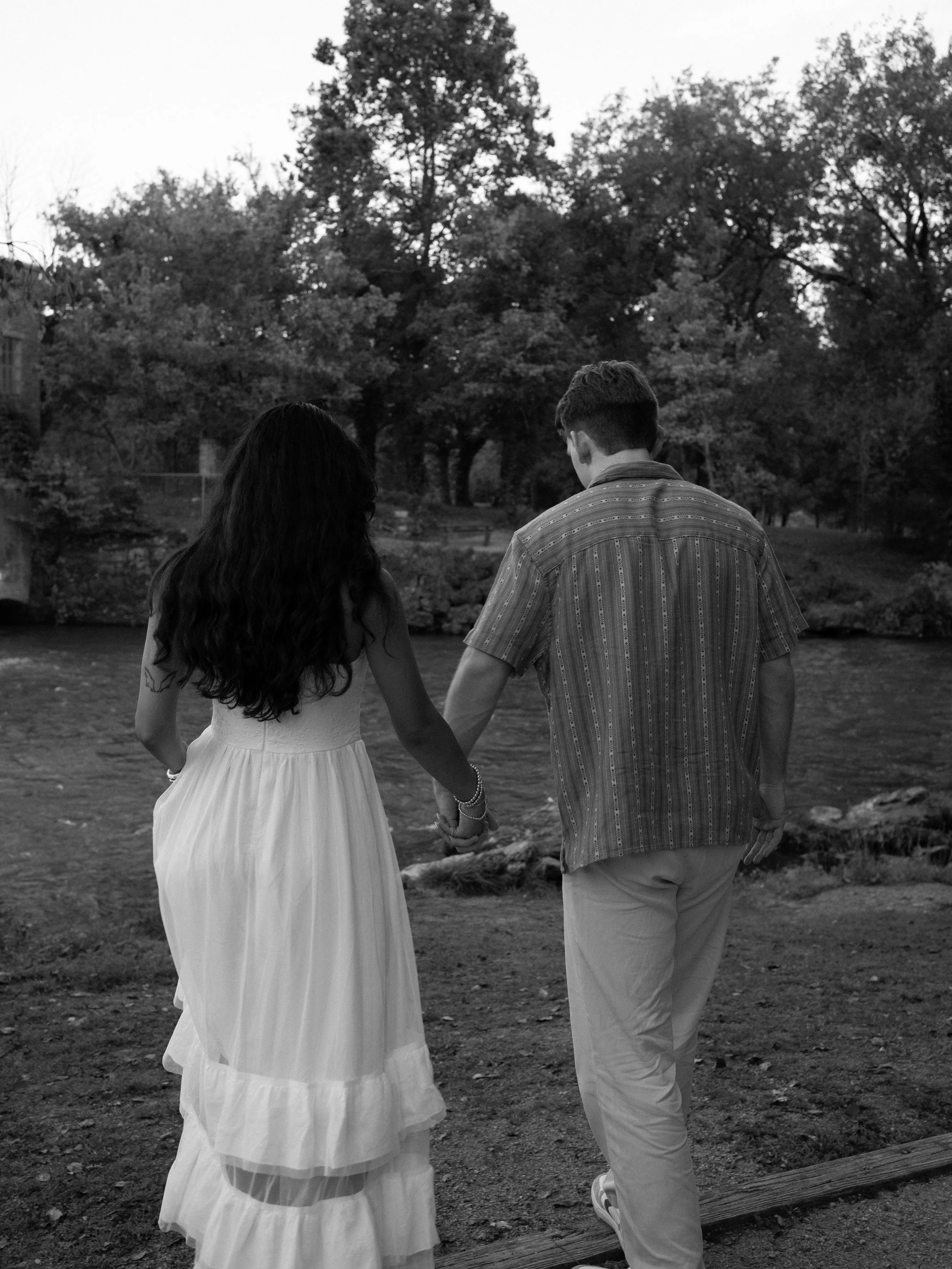 A quiet black-and-white moment in Mammoth Spring, Arkansas, as the couple walks hand in hand along the water.