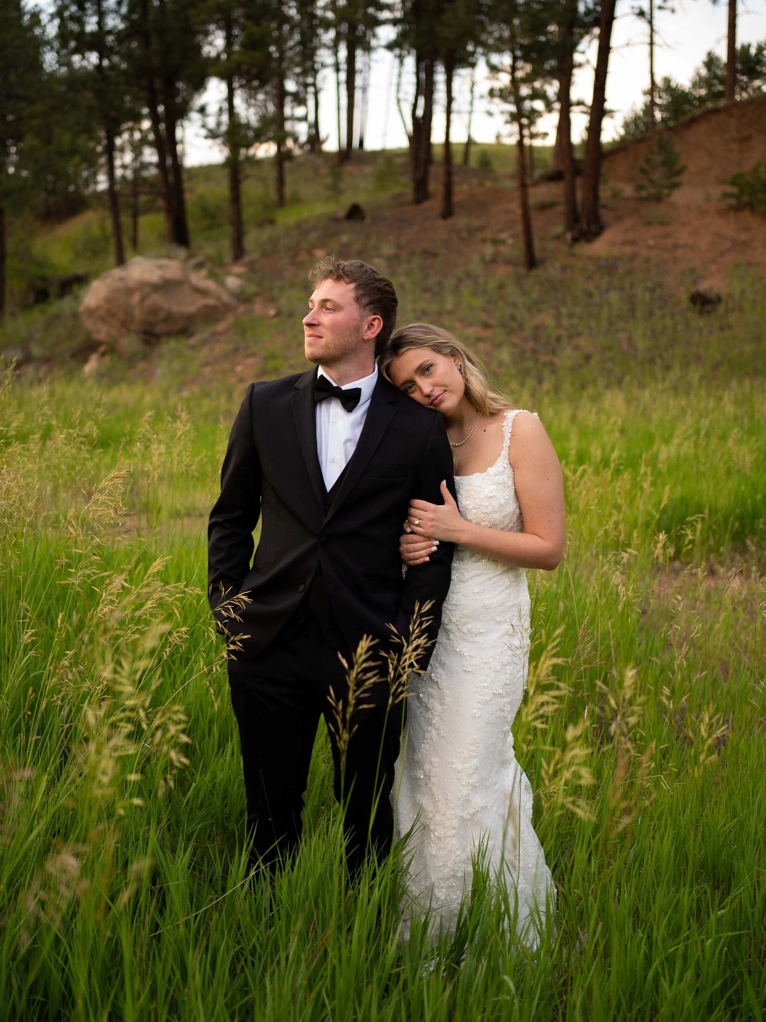 Bride and groom standing in a grassy field at Pikes Peak Ranch in Woodland Park Colorado with mountain views creating a romantic outdoor wedding portrait