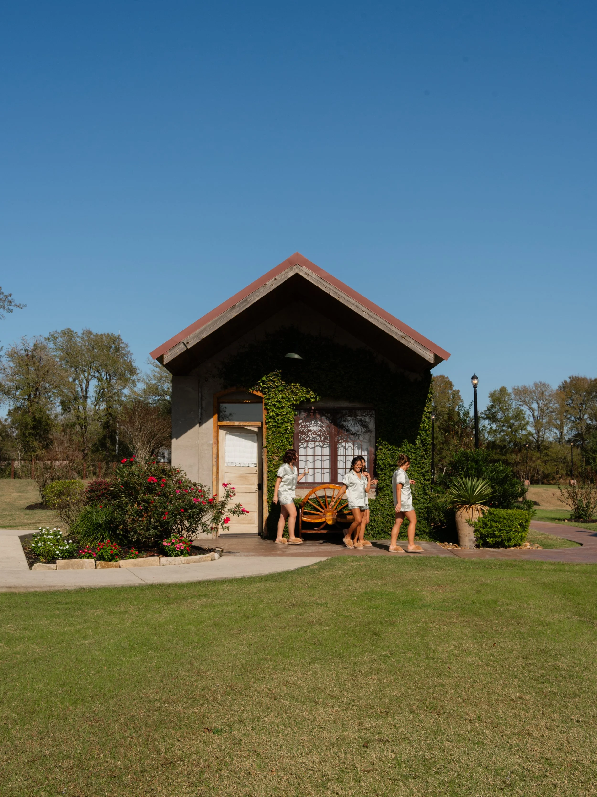 Candid photo of bridesmaids walking outside a Montgomery, Texas wedding bridal suite, surrounded by greenery and natural light.