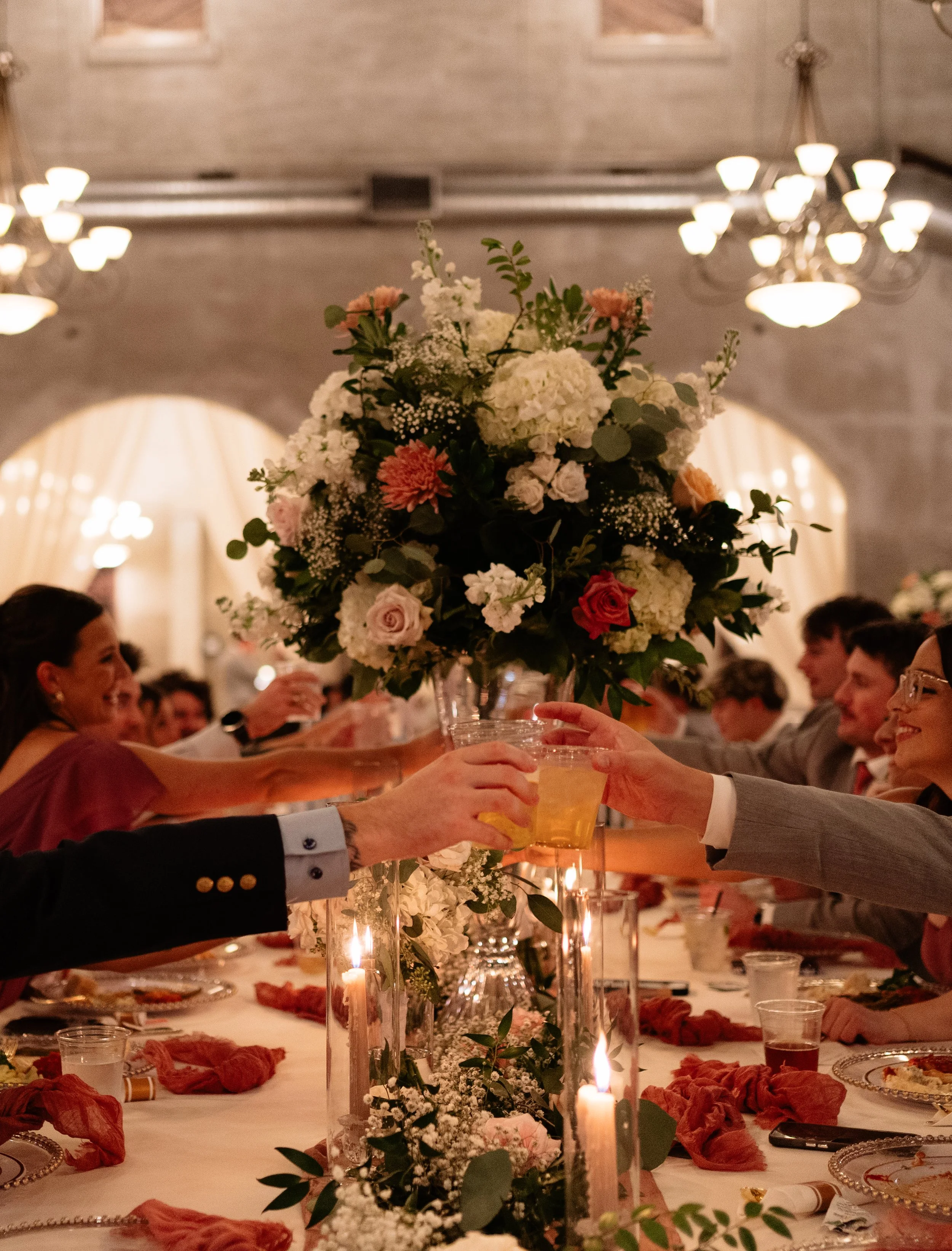 Guests raising a glass after toast with a detailed floral arrangement on table in Montgomery, TX, highlighting texture, color, and the intentional design of the wedding day.