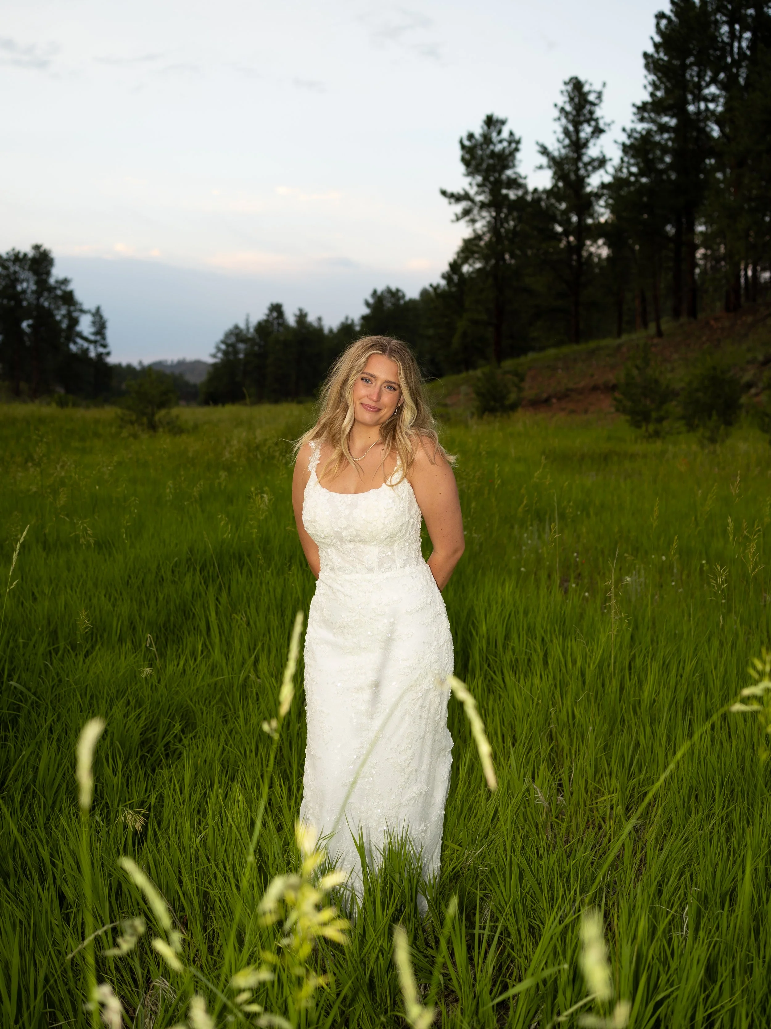 A soft and natural bridal portrait in Woodland Park, Colorado, surrounded by tall grass and warm evening light.