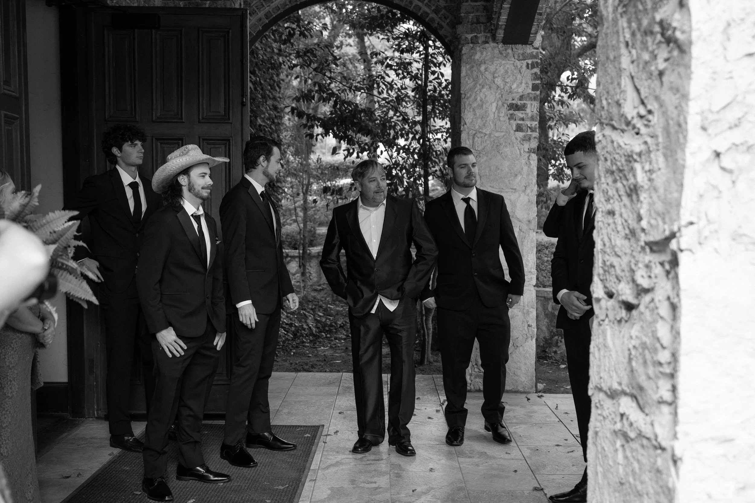 A candid black-and-white moment in Waxahachie, TX, capturing connection and personality among the groomsmen.