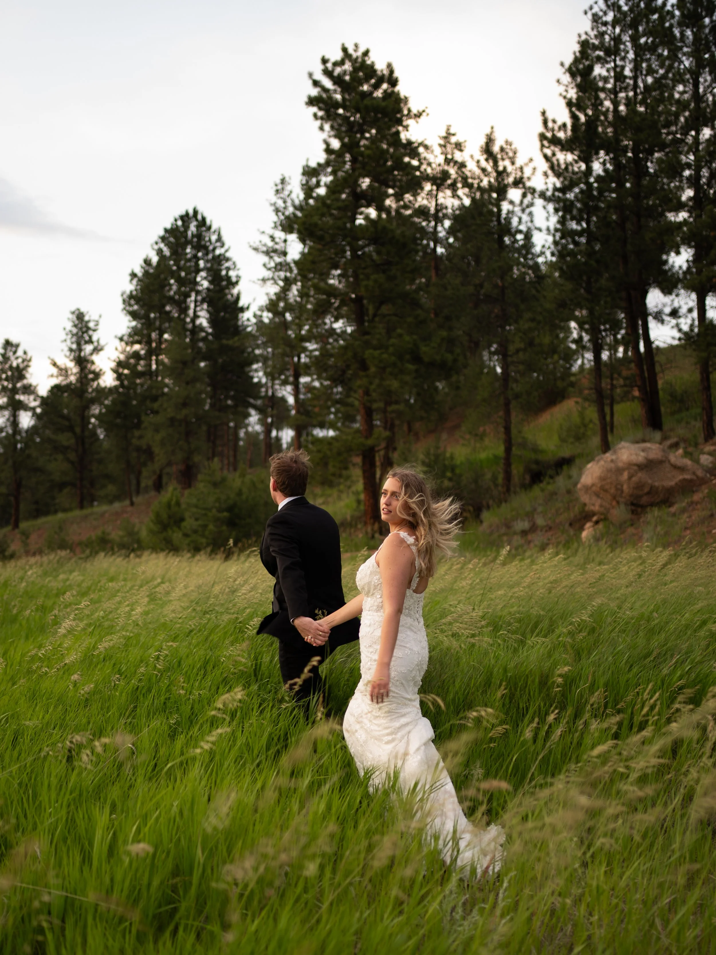 A natural and movement-filled portrait at Pikes Peak Ranch, capturing the couple walking through tall grass and open space.