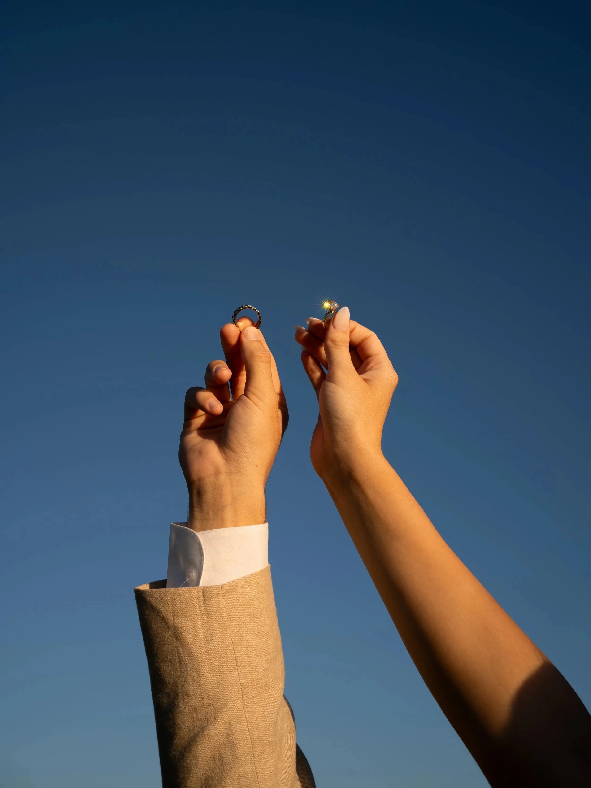 Wedding detail moment in Fort Worth Texas with rings held in natural light against a blue sky