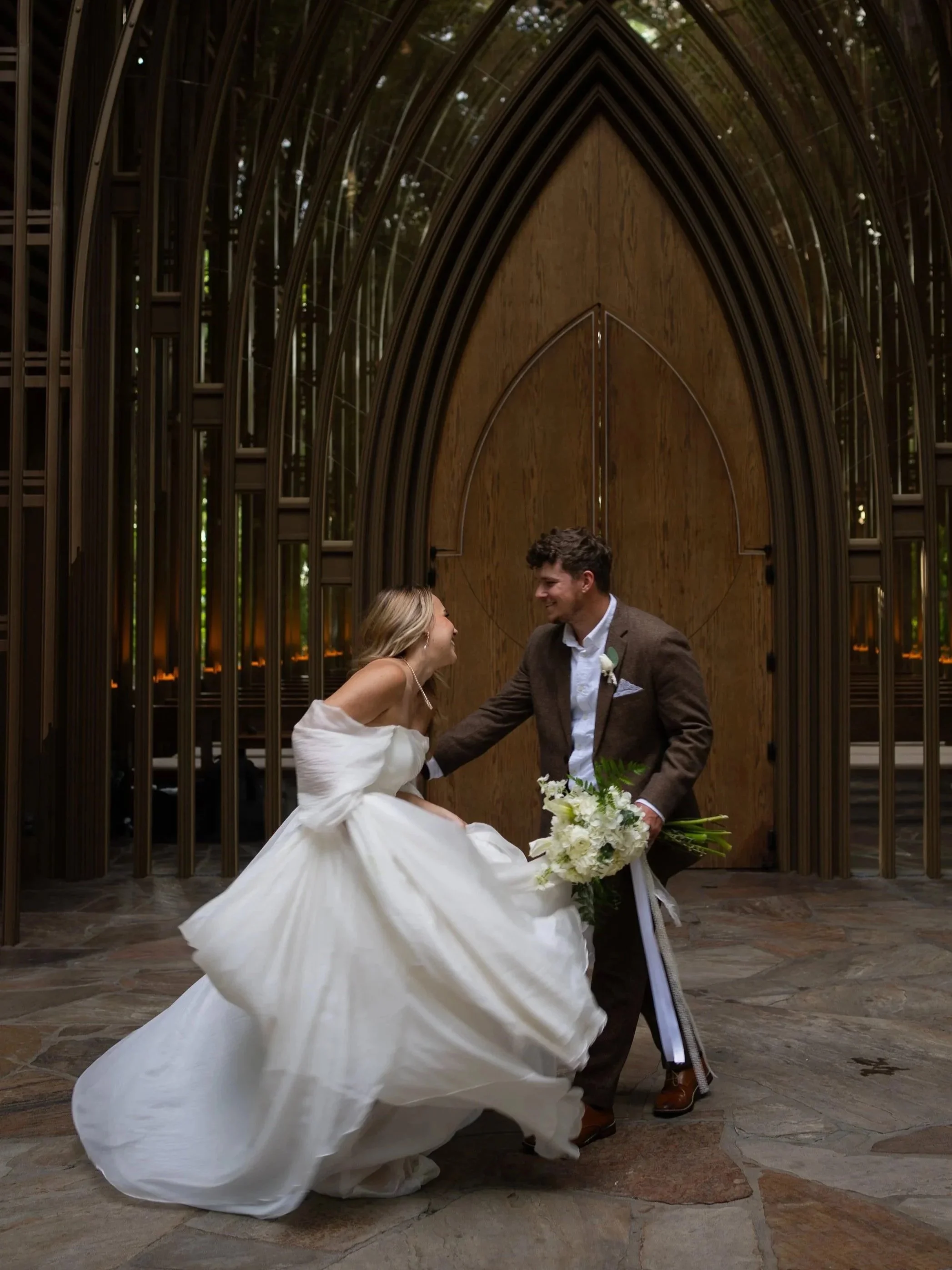Couple spinning together in front of an architectural doorway during a wedding in Bella Vista Arkansas