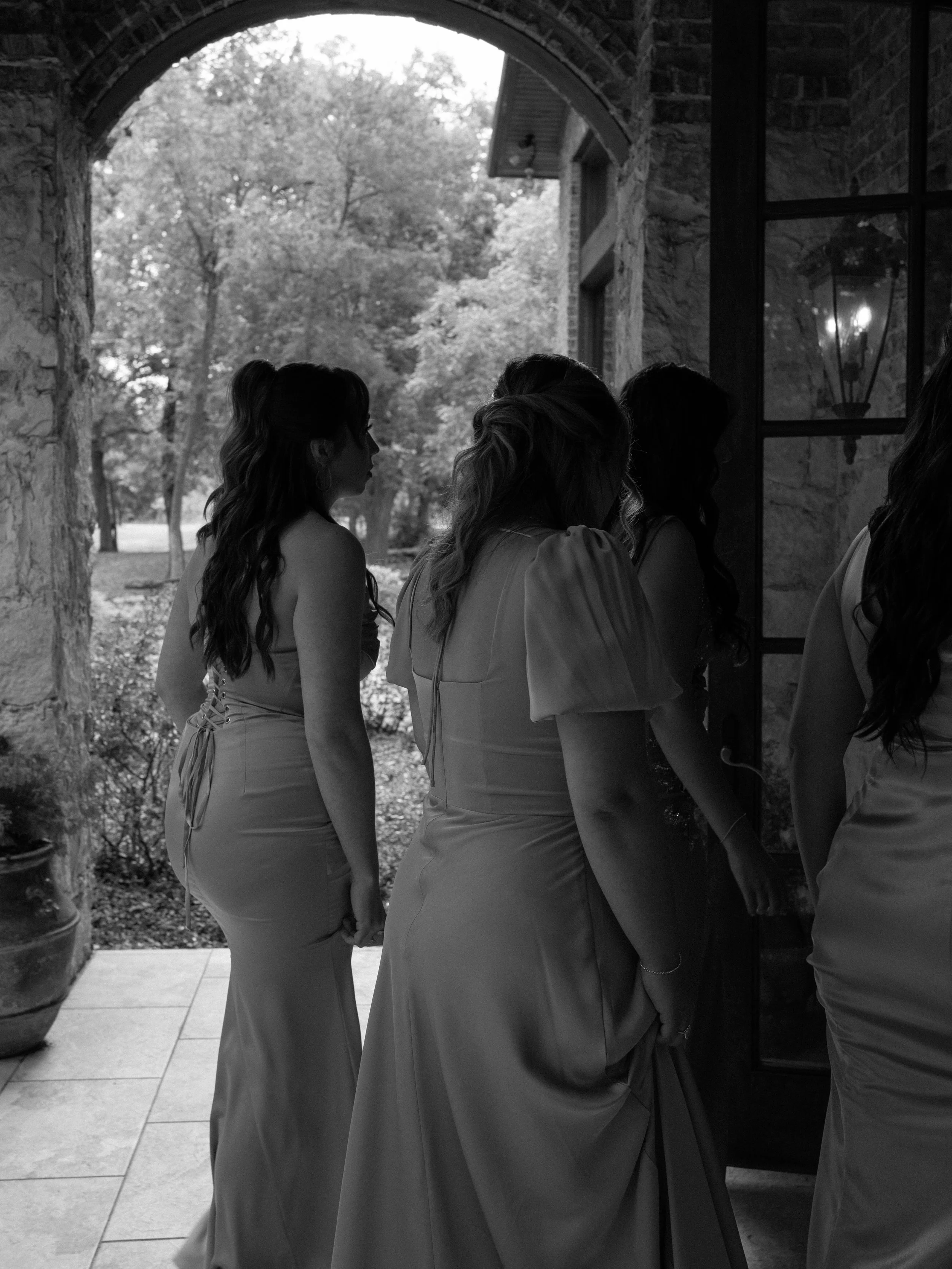 A candid black-and-white moment in Waxahachie, TX, capturing connection and anticipation among the bridesmaids.