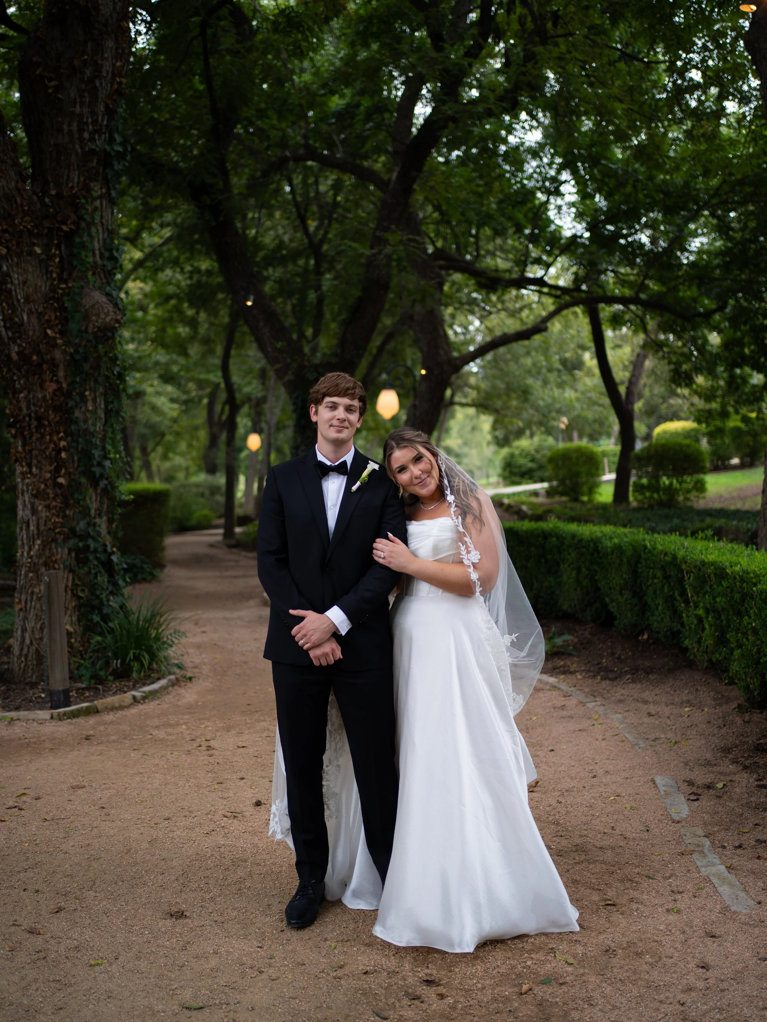 A soft and romantic portrait in Waxahachie, Texas, capturing the couple in a quiet garden setting.
