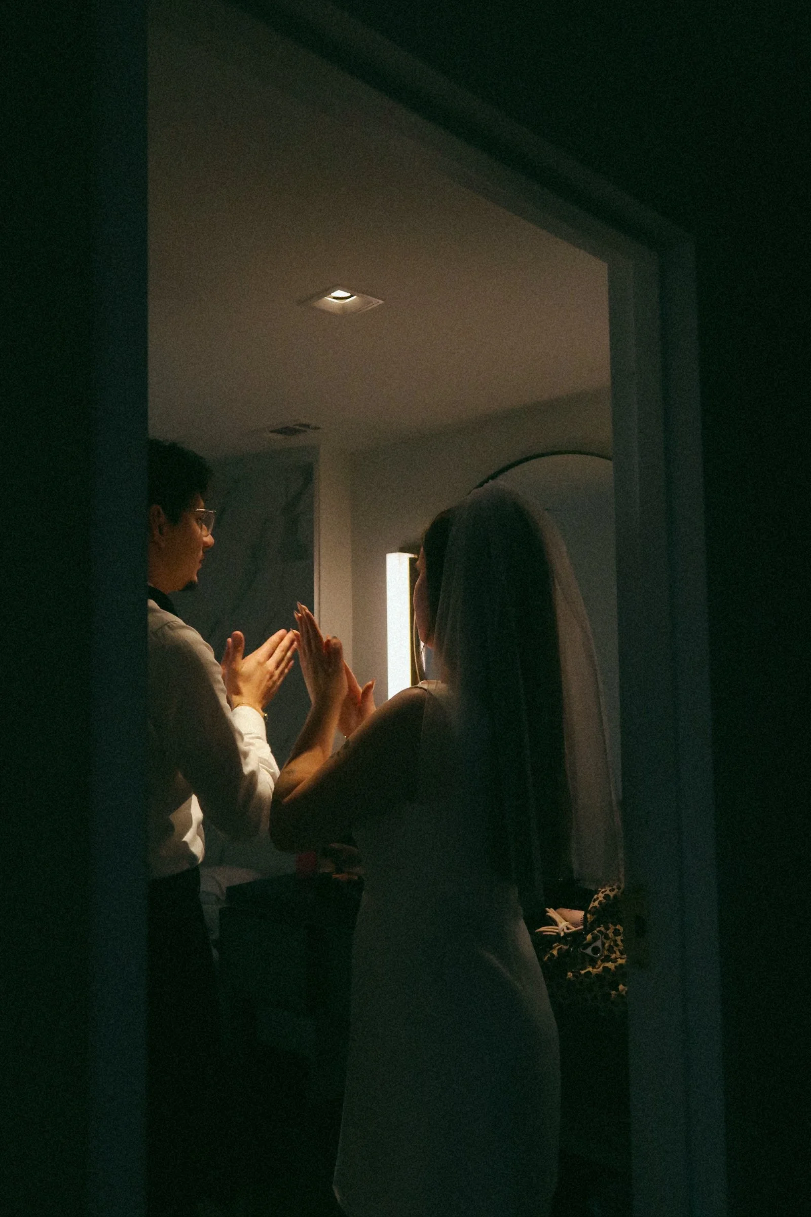 An intimate reflection of the couple getting ready in Houston, TX, framed through a mirror for a layered, storytelling perspective.