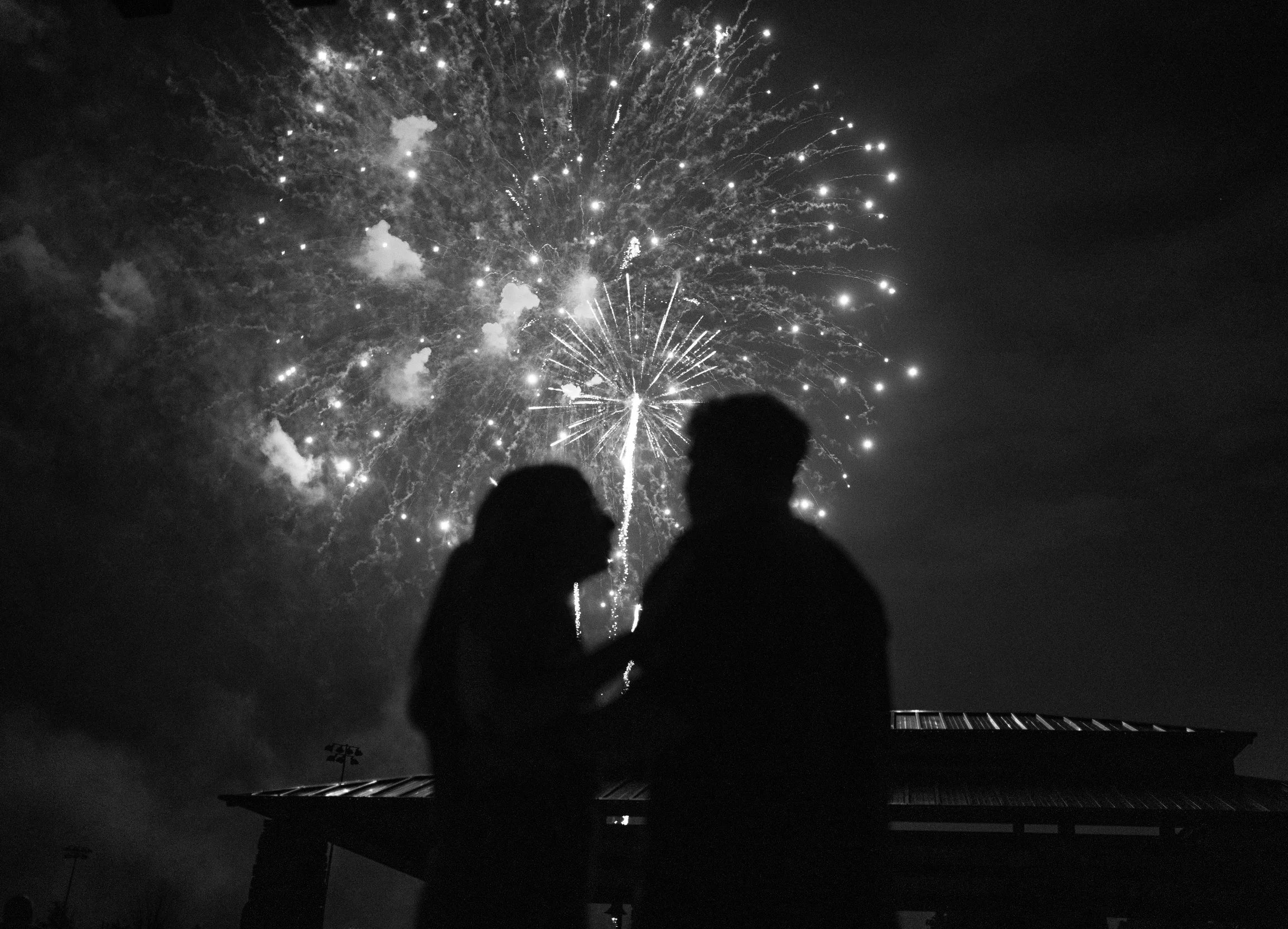 Silhouette of bride and groom watching fireworks at night