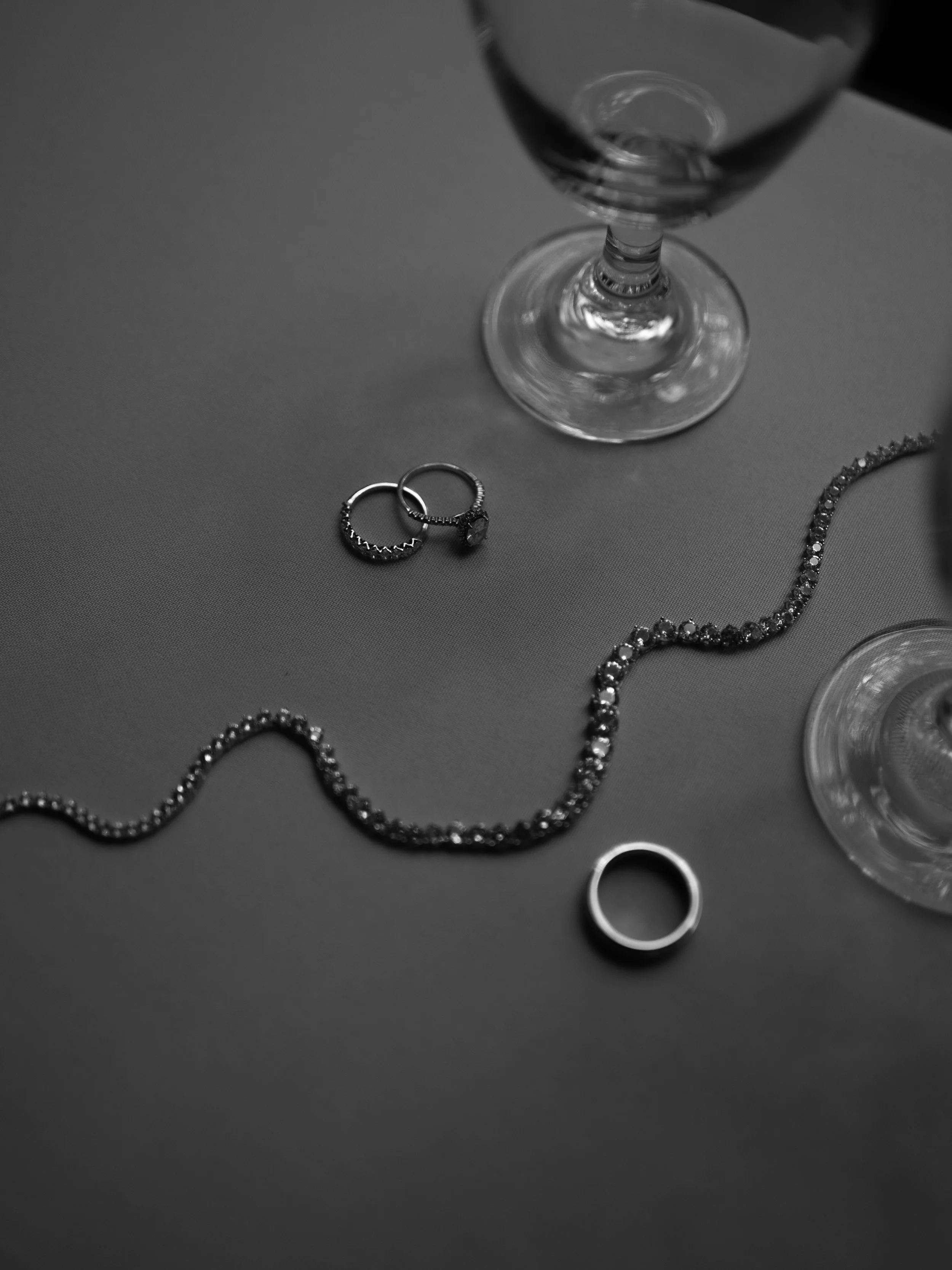 A refined black-and-white detail of wedding rings and jewelry in Waxahachie, TX, emphasizing texture and composition.